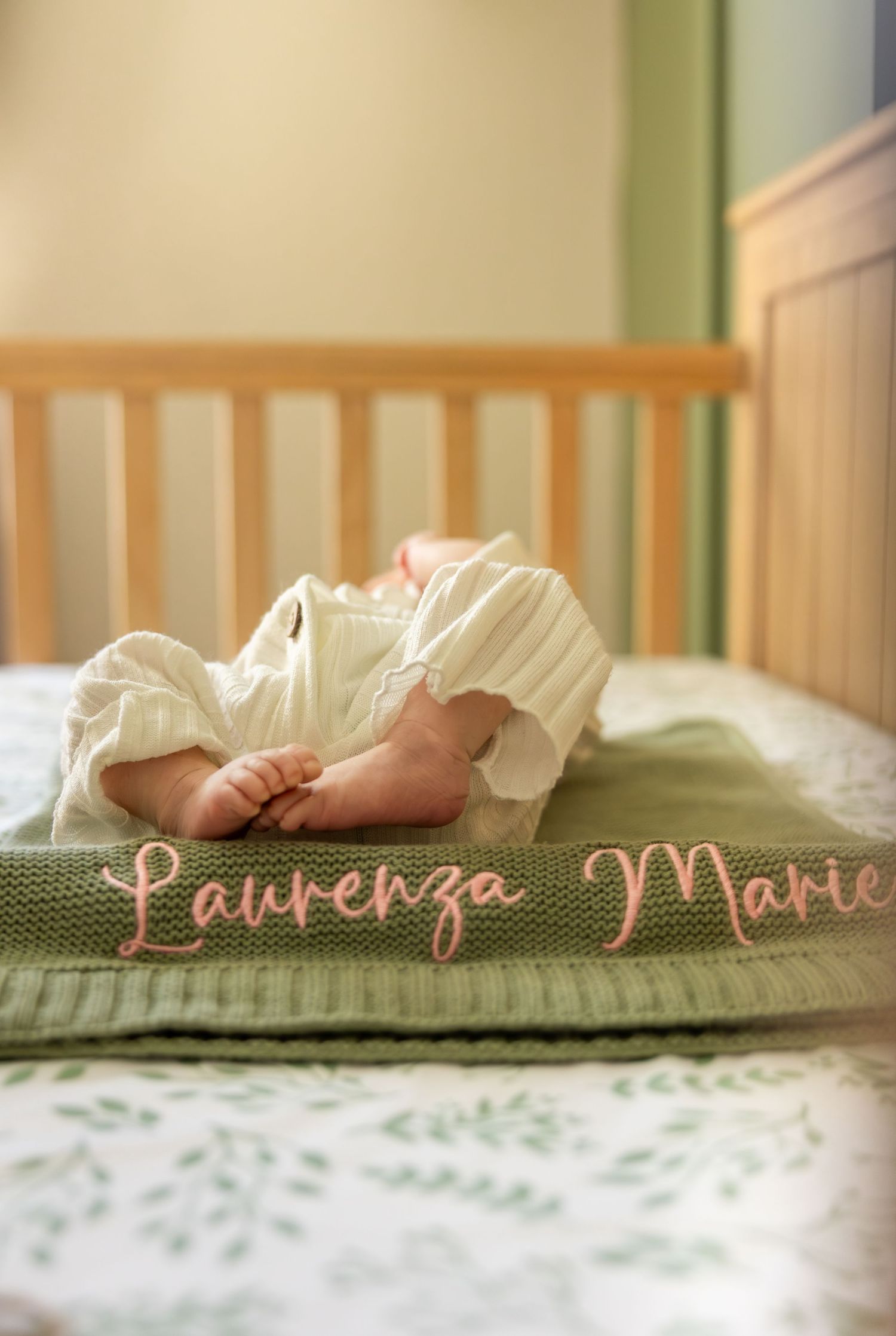 Close-up of tiny baby feet resting on a floral patterned blanket with cursive text.