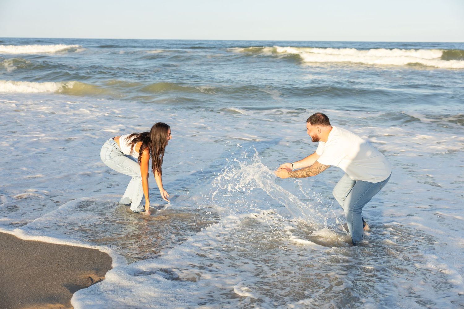Couple playing and splashing in ocean waves at the beach.