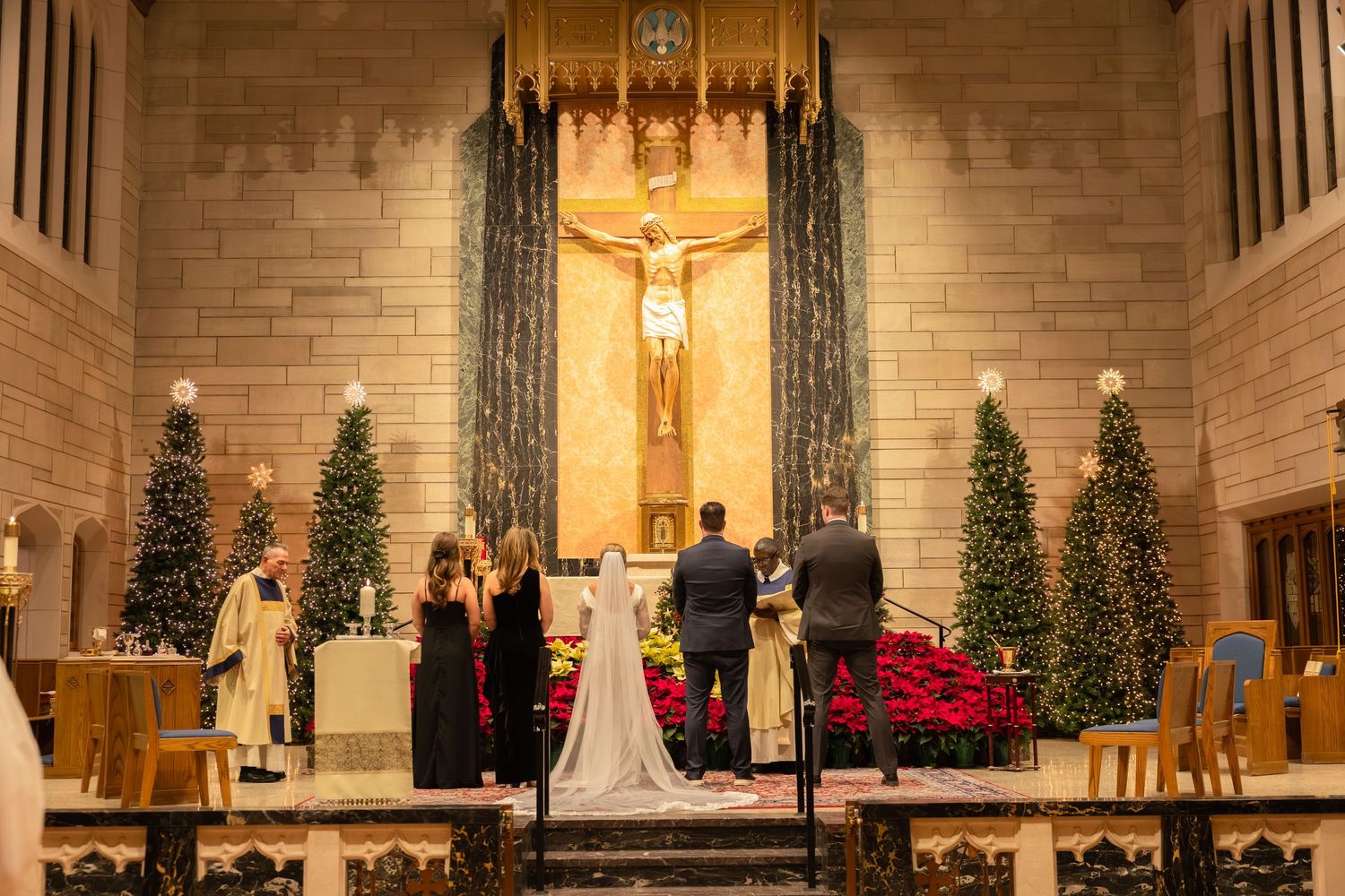 Church altar decorated with poinsettias and Christmas trees illuminated by warm lighting.