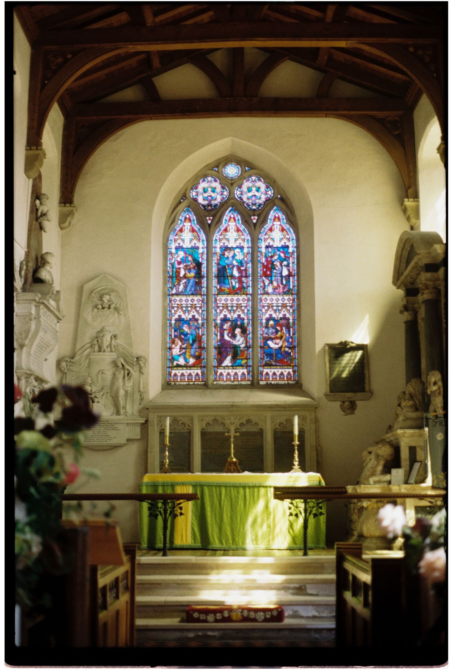 Sunlit church altar with colorful stained glass window and green altar cloth.