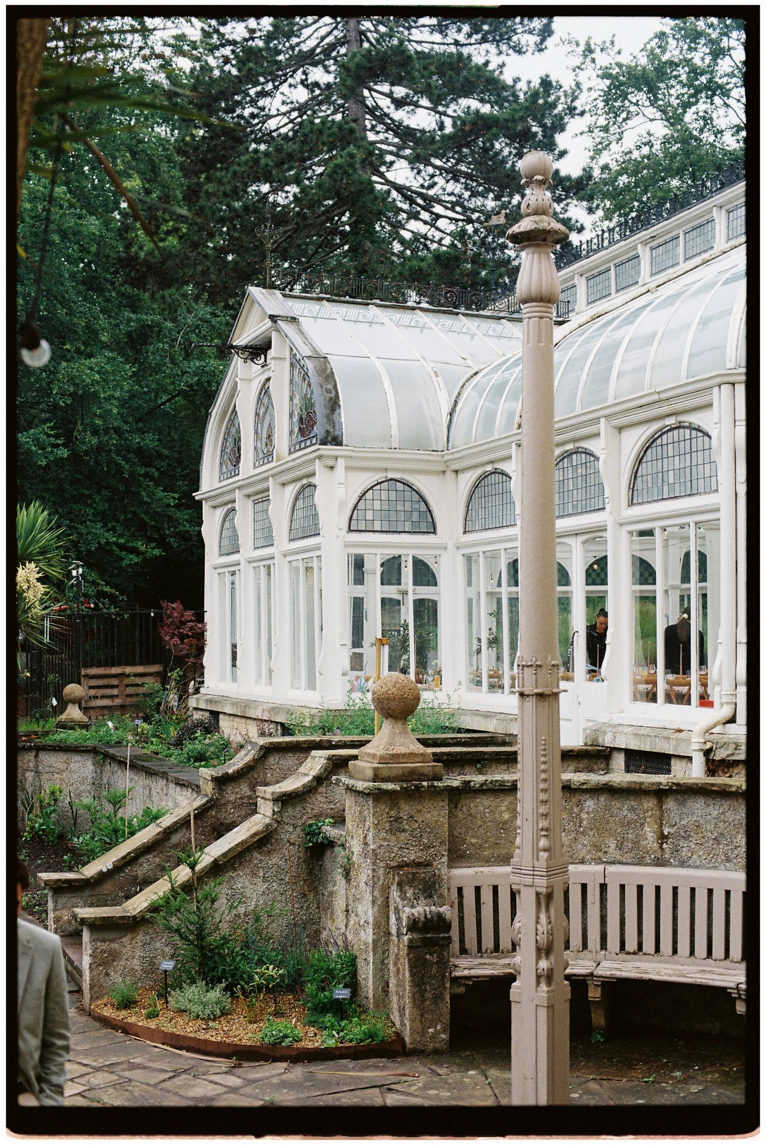 Beautiful Victorian glass conservatory wedding venue surrounded by lush gardens and stone terraced walls.