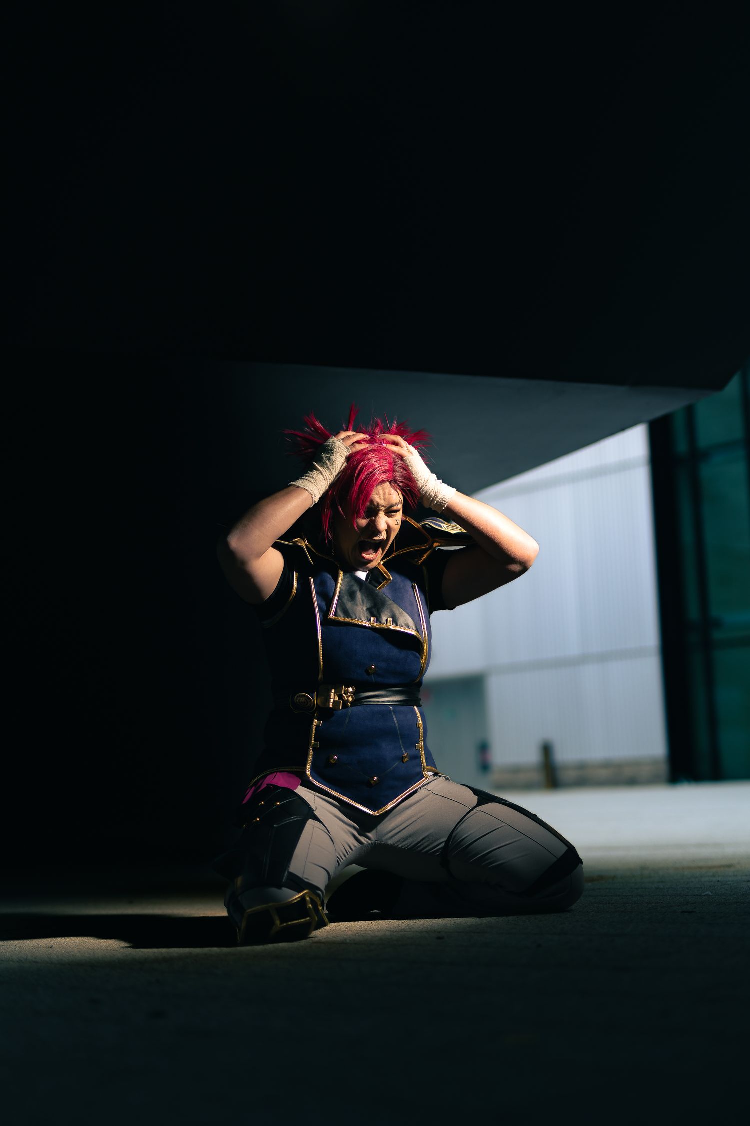 Dramatic cosplay photo of figure in navy uniform against stark lighting.