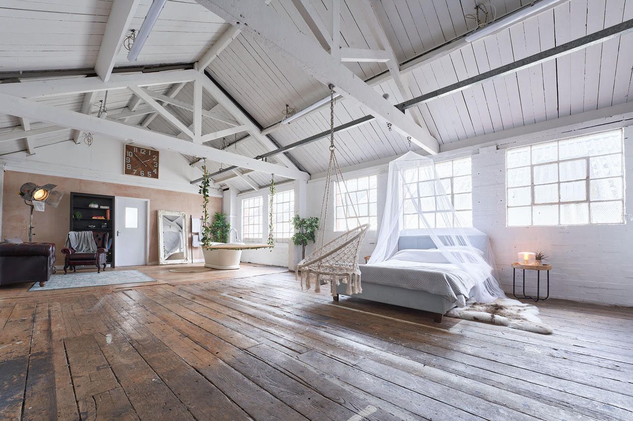 Bright white industrial loft studio space with exposed beams, hardwood floors, and large windows letting in natural light.