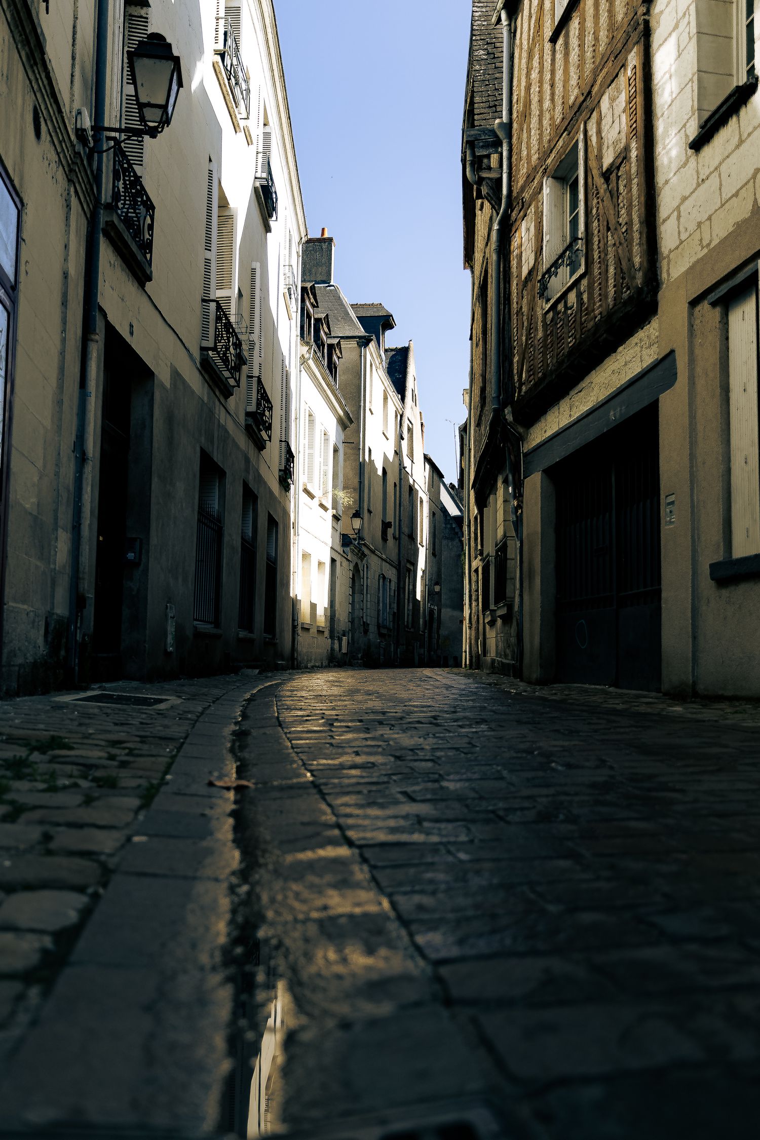Narrow cobblestone alley flanked by tall historic buildings in a quiet European old town street.