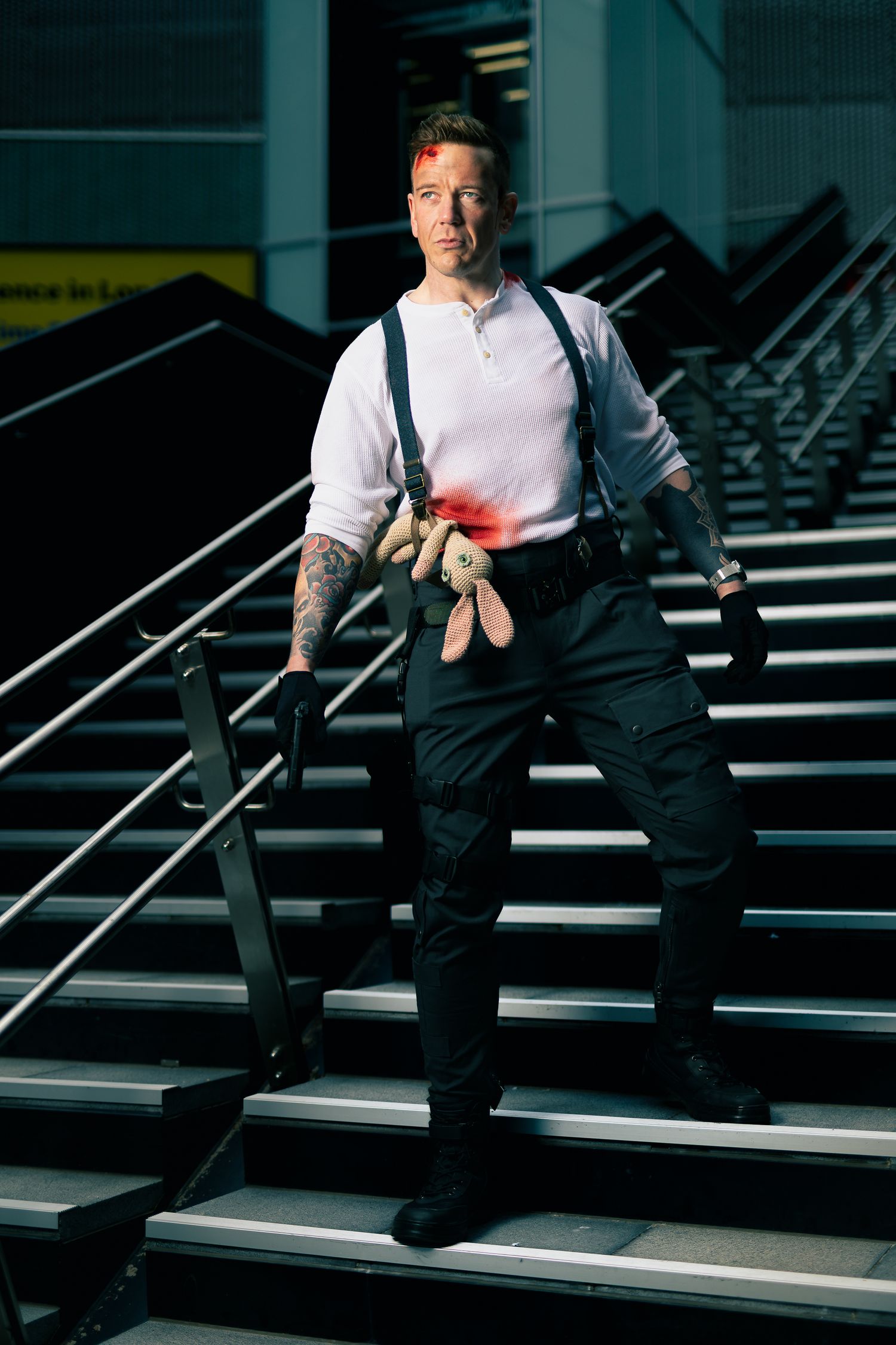 A person in business attire stands confidently on dark stairs with dramatic lighting and shadows.