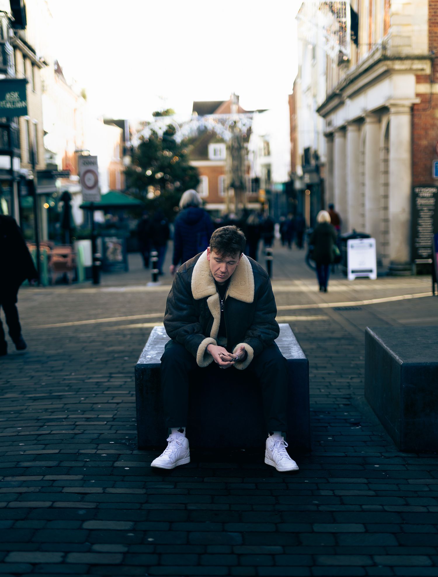 Urban scene with person sitting on paved street surrounded by historic buildings.