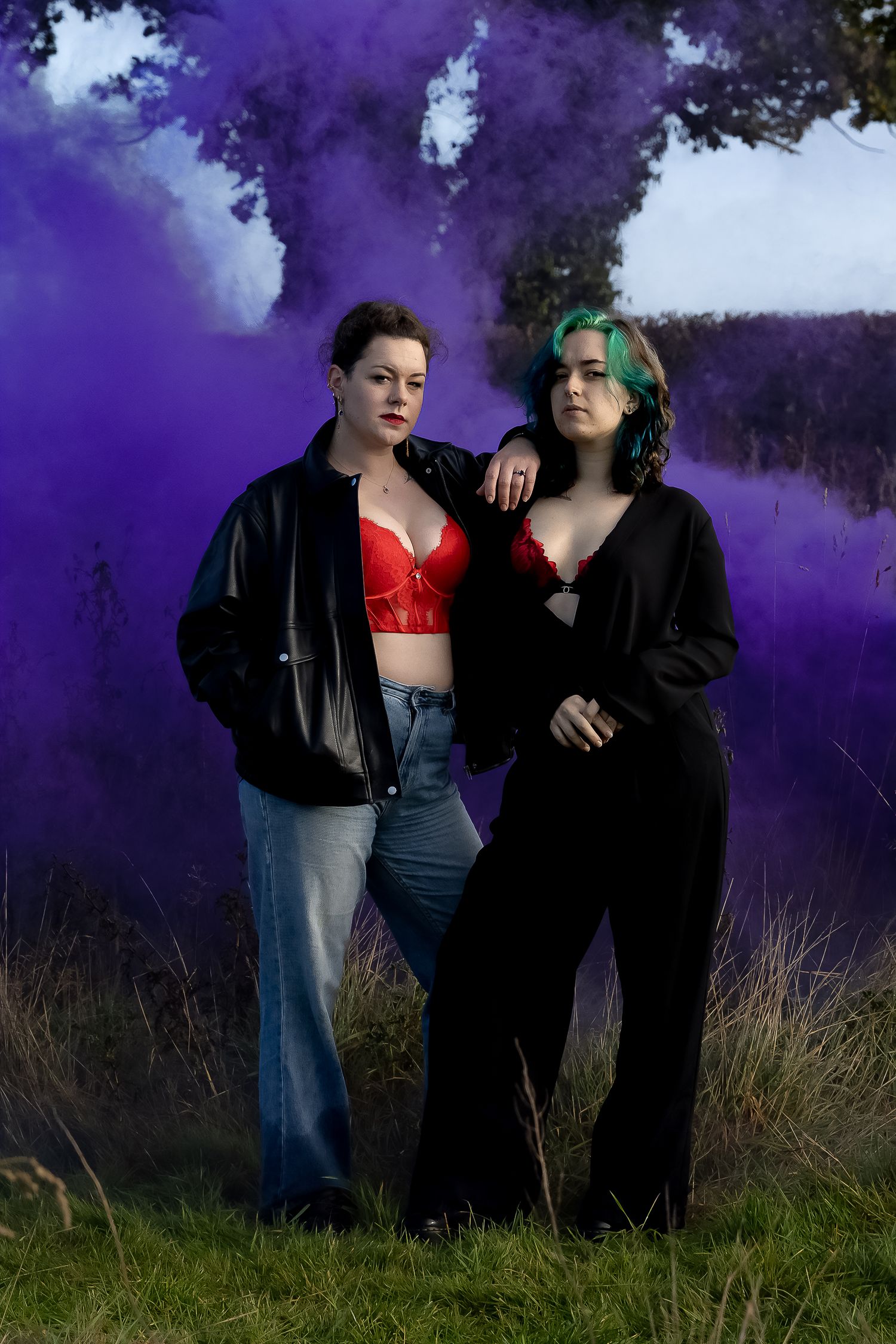 Alternative style portrait with purple smoke effects and black clothing in field setting.