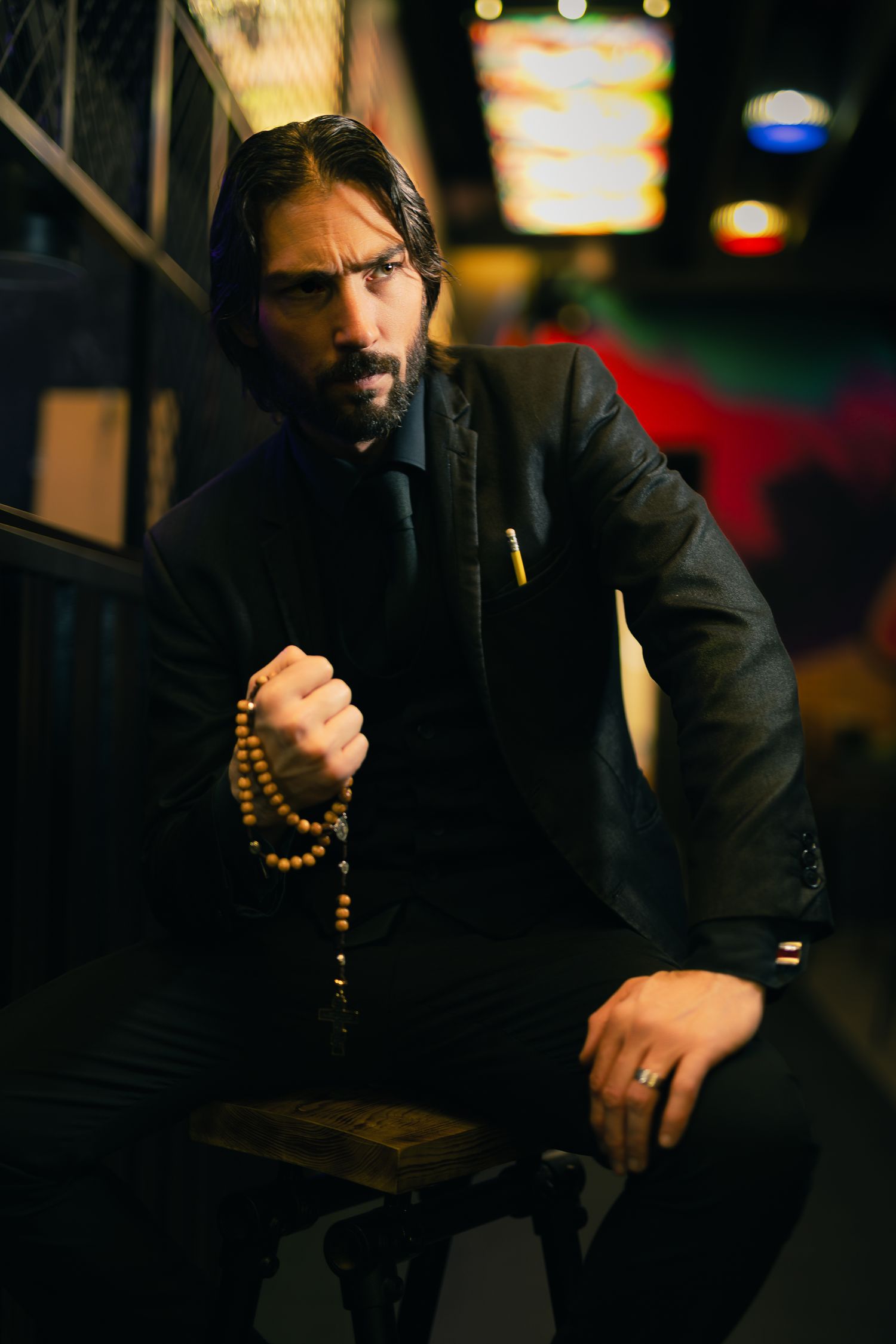 Dark moody portrait series of a figure in black clothing with beaded accessories.
