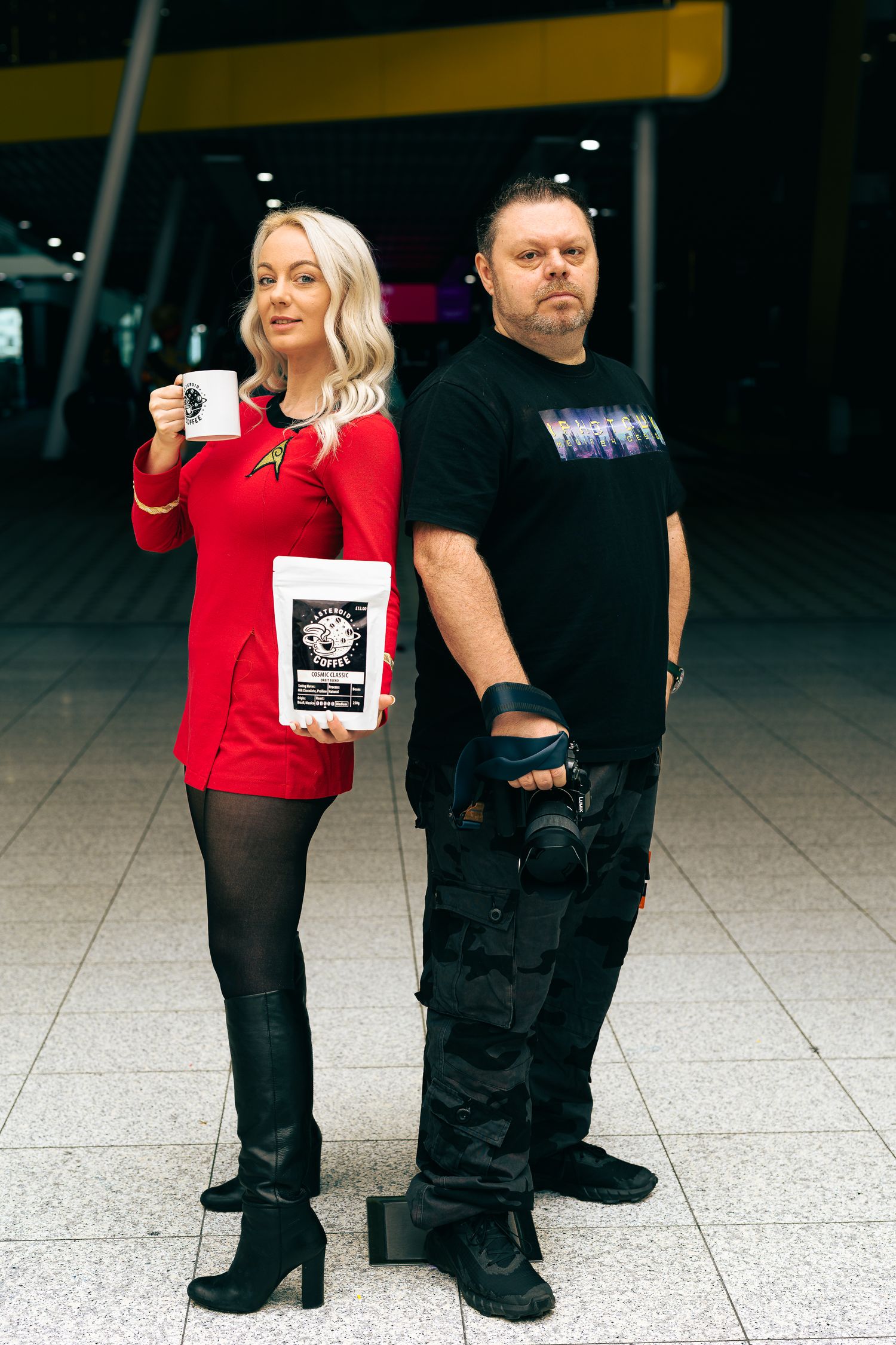 Personal branding portrait of two people standing back-to-back holding coffee product and a camera