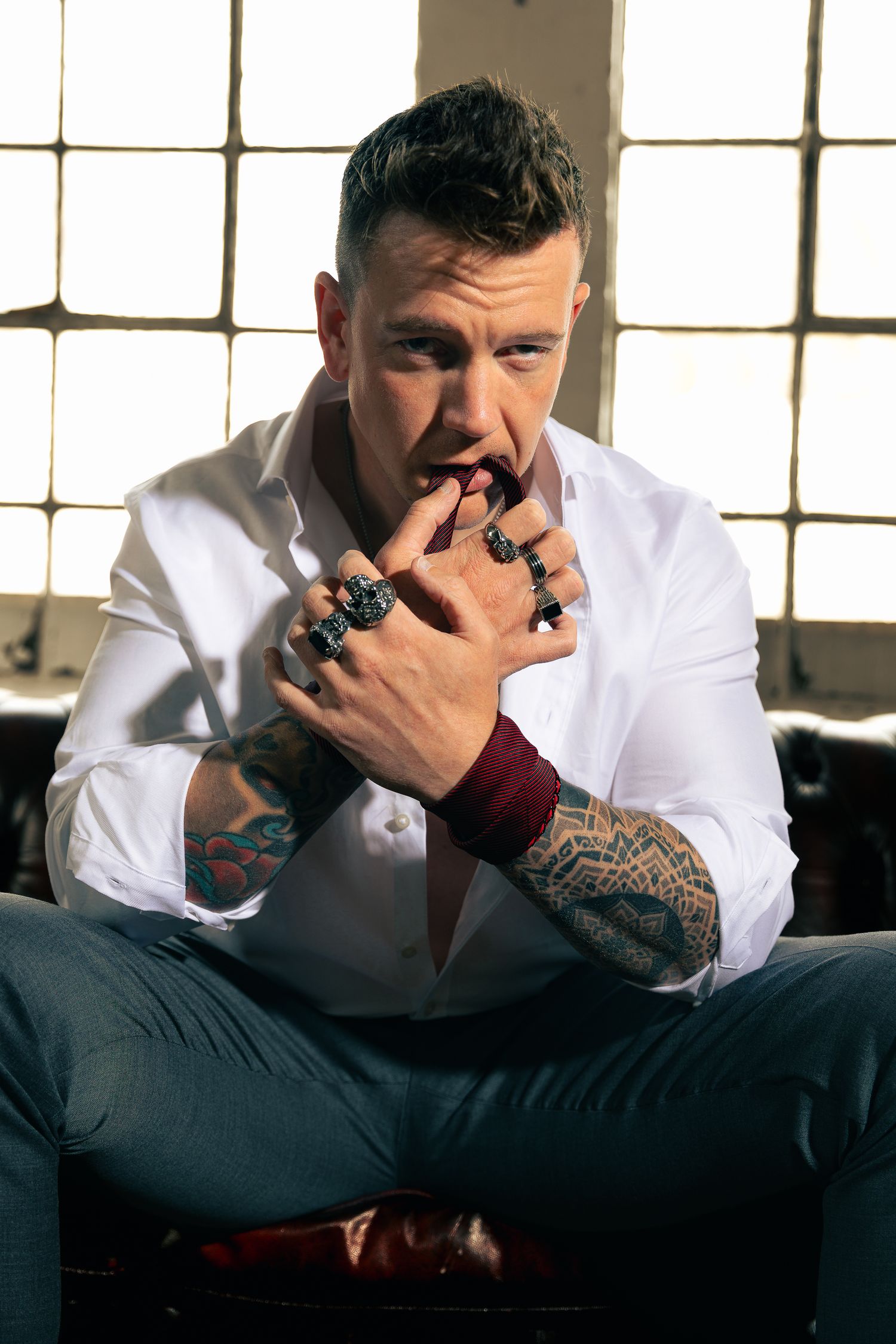 Close-up portrait showing multiple statement rings and tattoos in natural light.