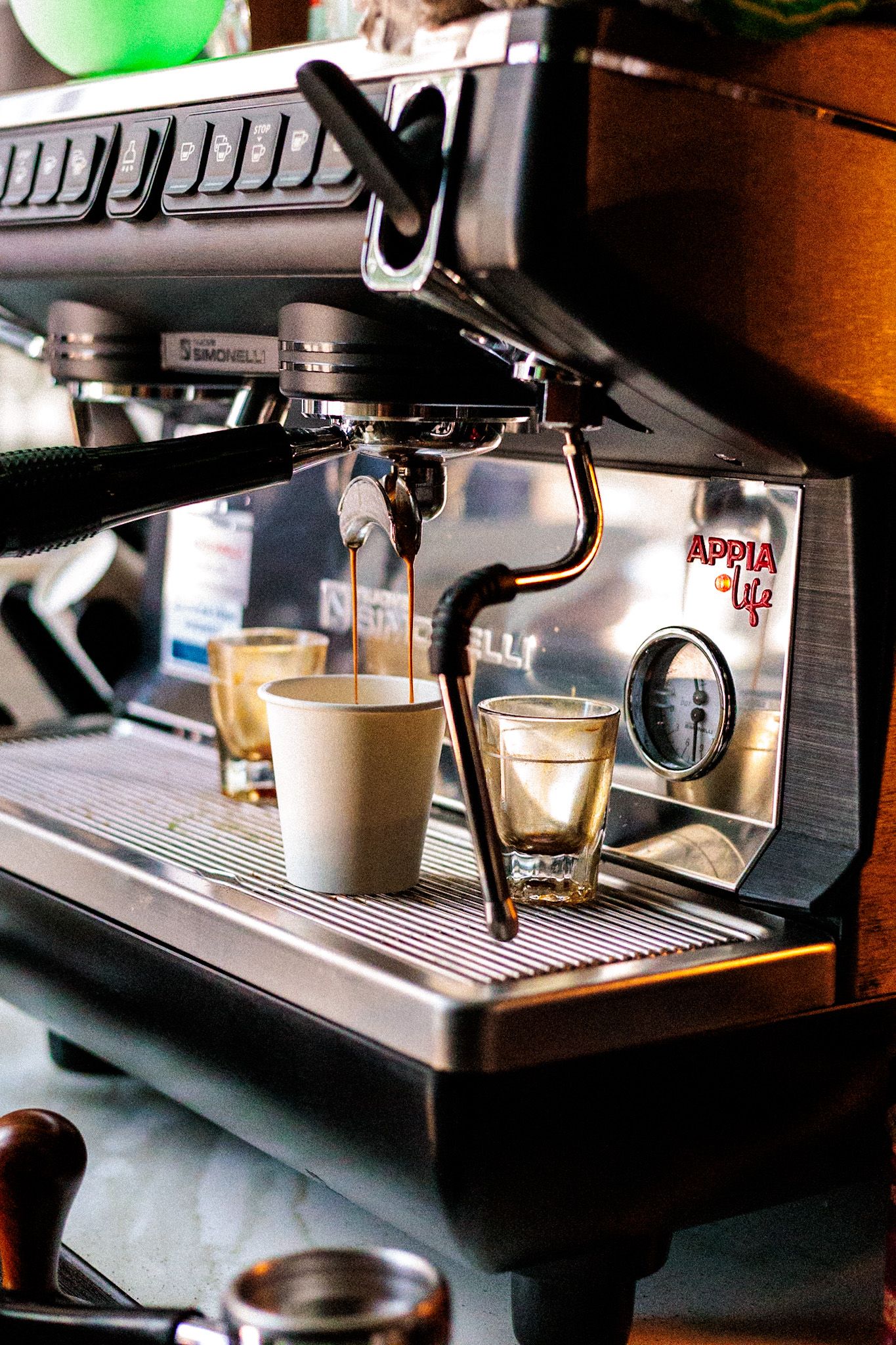 A Sanremo Appia Life espresso machine brewing shots into small cups on a cafe counter.