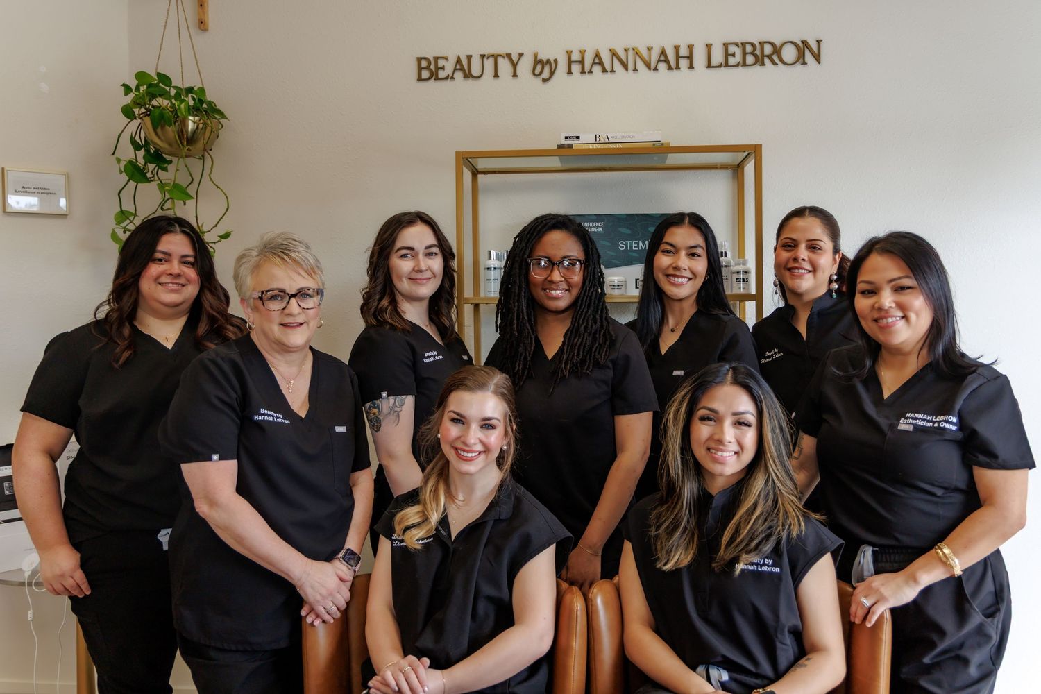 Beauty by Hannah LeBron salon team of nine staff members posing together in matching black uniforms.