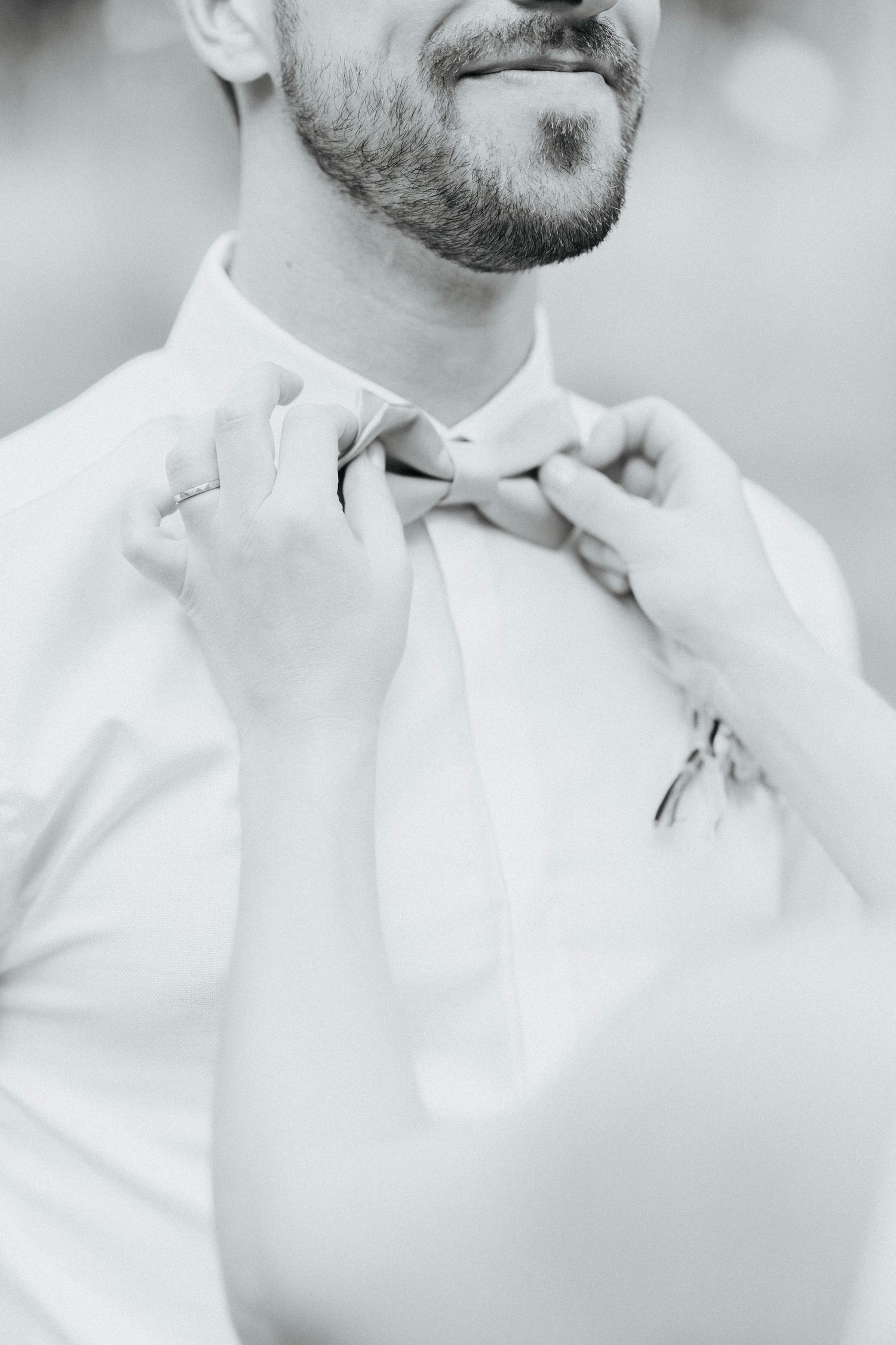 bride adjusting grooms bow tie, close up