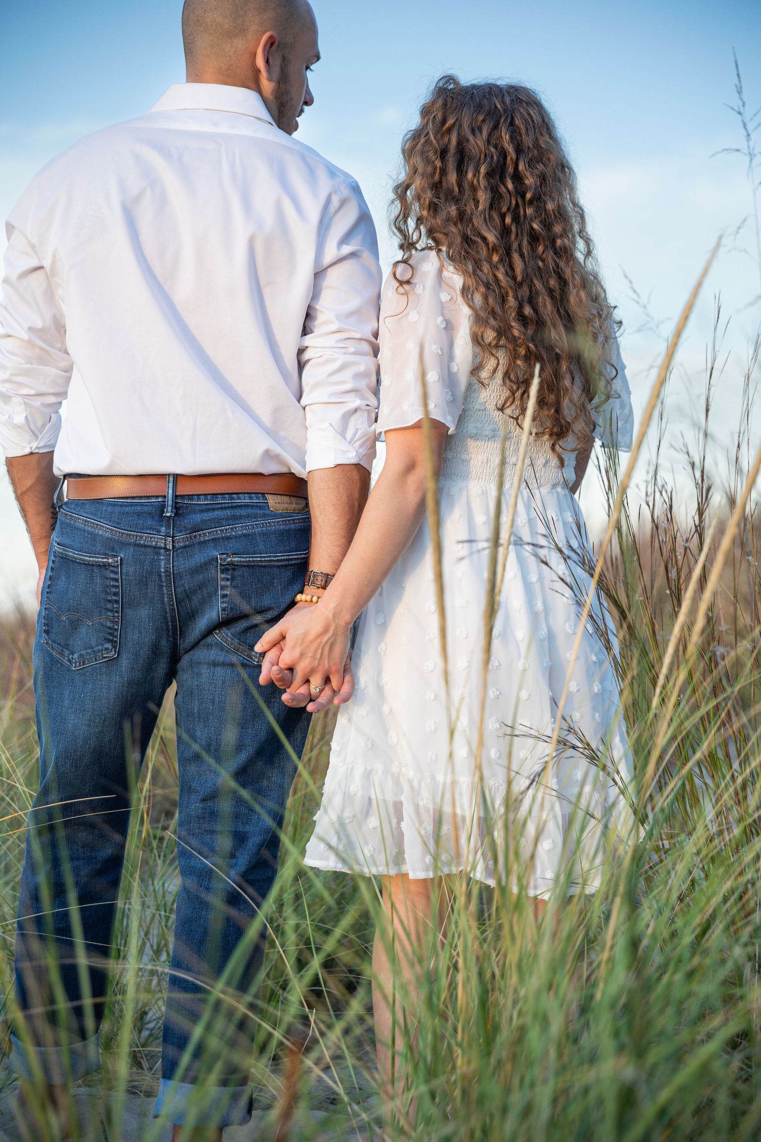 Engaged couple embracing along a Lake Michigan beach in Indiana during a natural, candid engagement session.