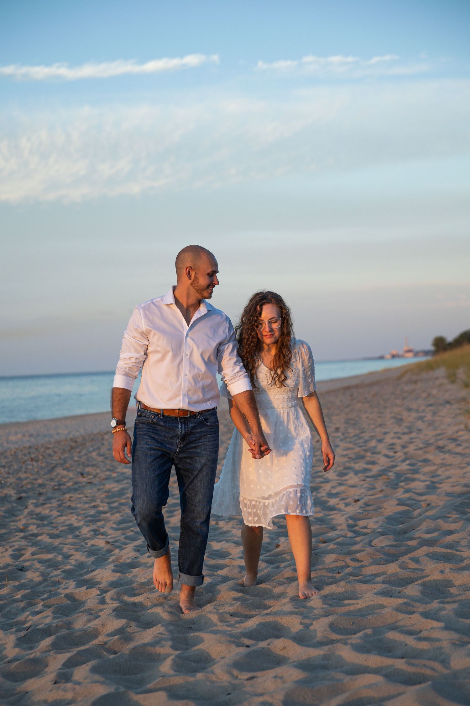 Engaged couple walking along a Lake Michigan beach in Indiana during a natural, candid engagement session.