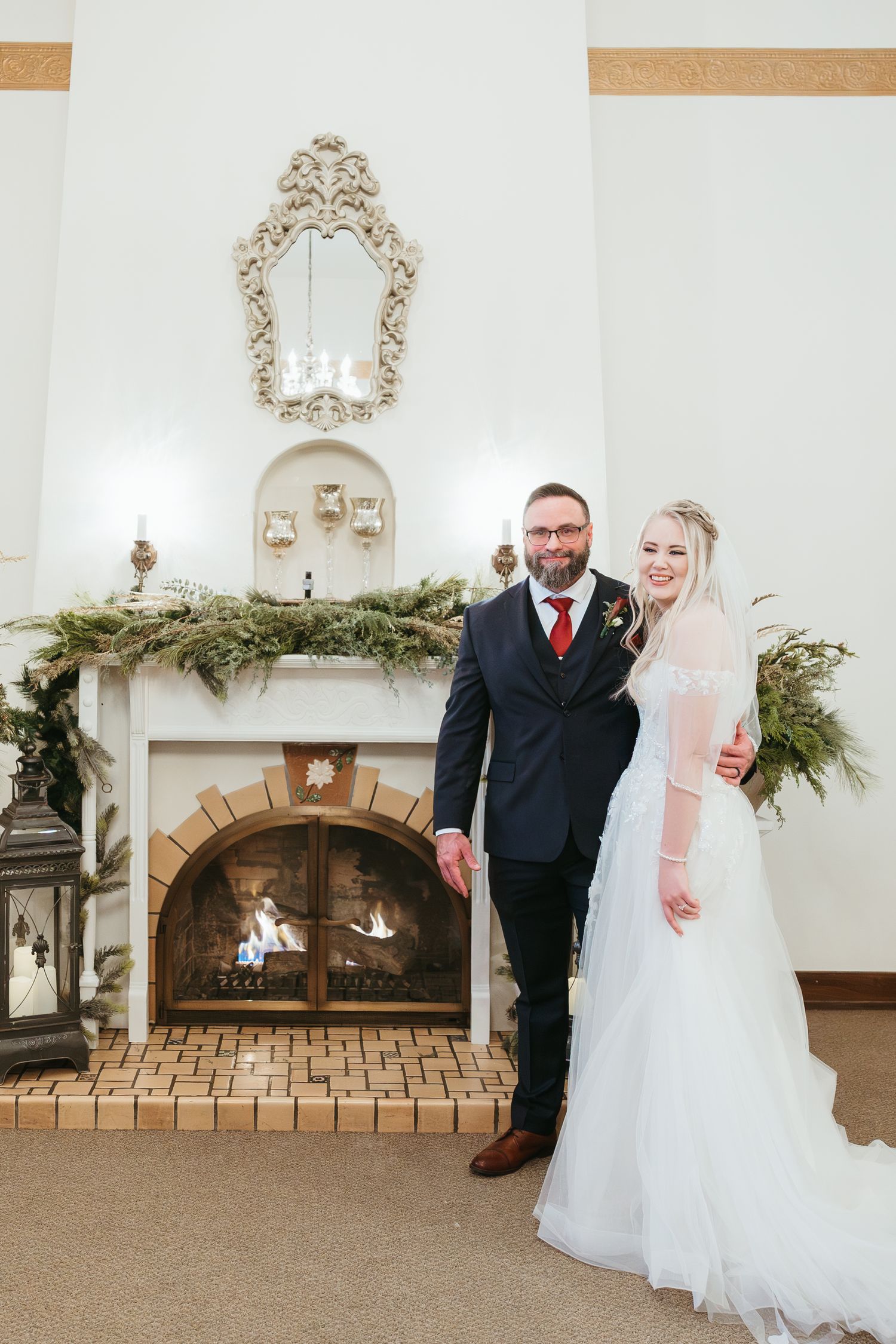 Bride and groom portrait at a winter wedding in Michigan standing together indoors beside a cozy fireplace