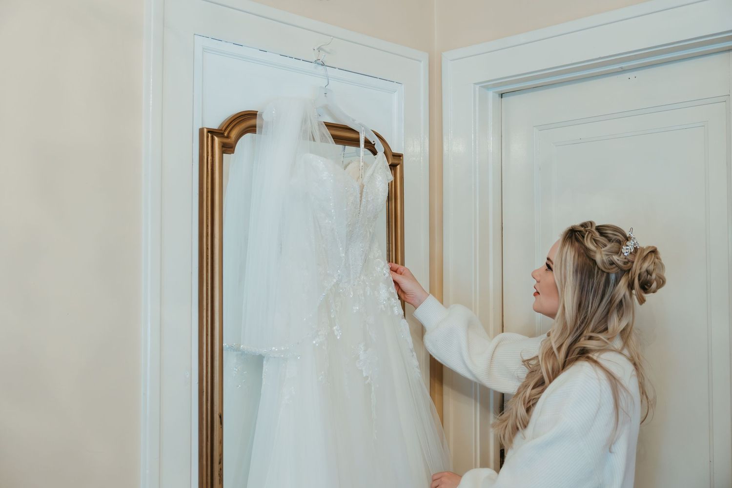 Bride looking at her wedding dress while getting ready during a Michigan wedding in soft natural light