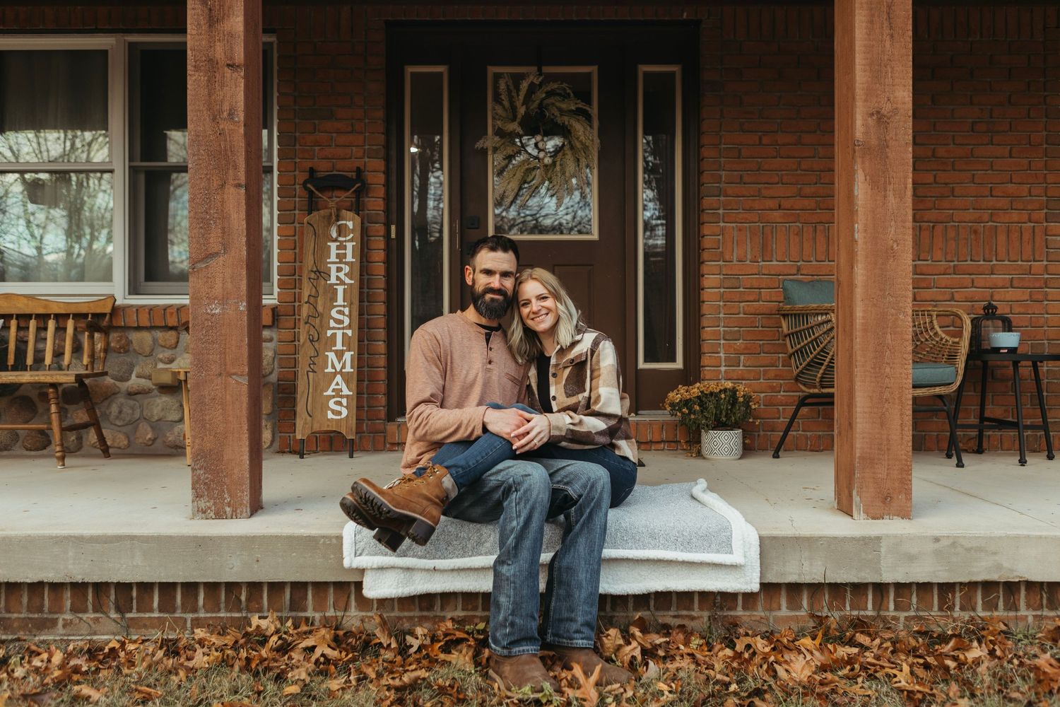 Cozy winter engagement session in Lapeer, Michigan with a couple standing together on a porch in soft natural light