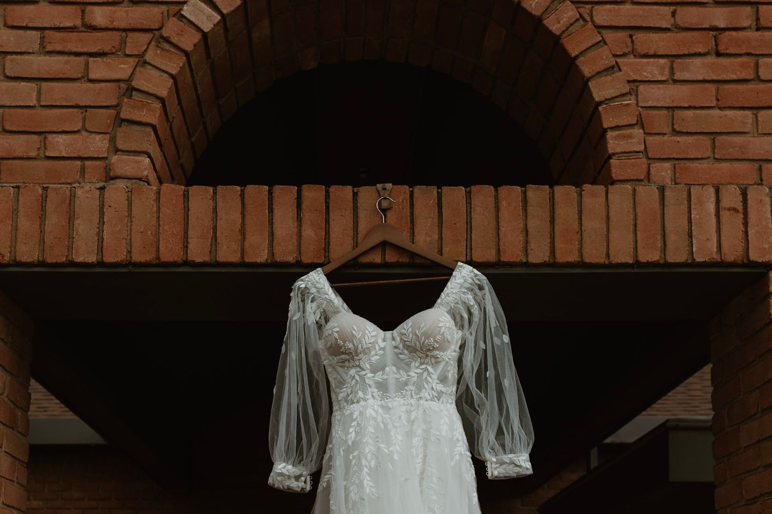 Wedding dress hanging against a brick building during a Michigan wedding, captured in natural light