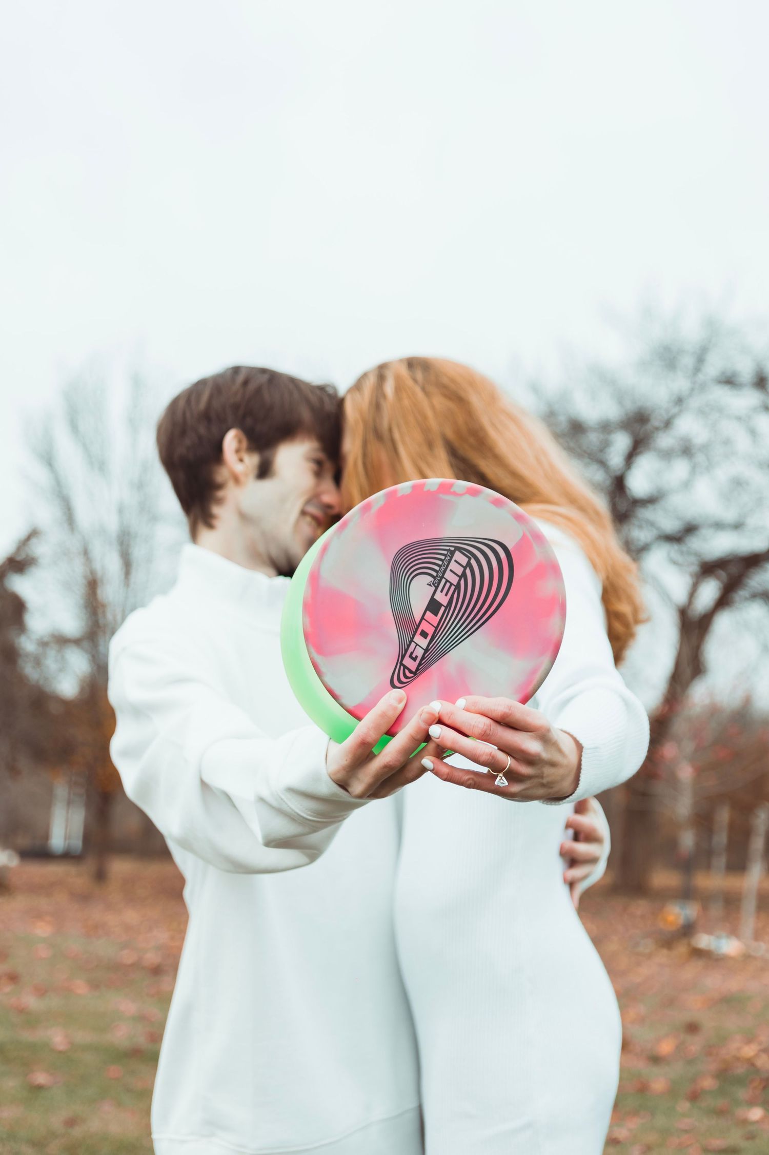 Fall engagement session in Oakland County, Michigan featuring a couple holding a disc golf disc in an outdoor setting