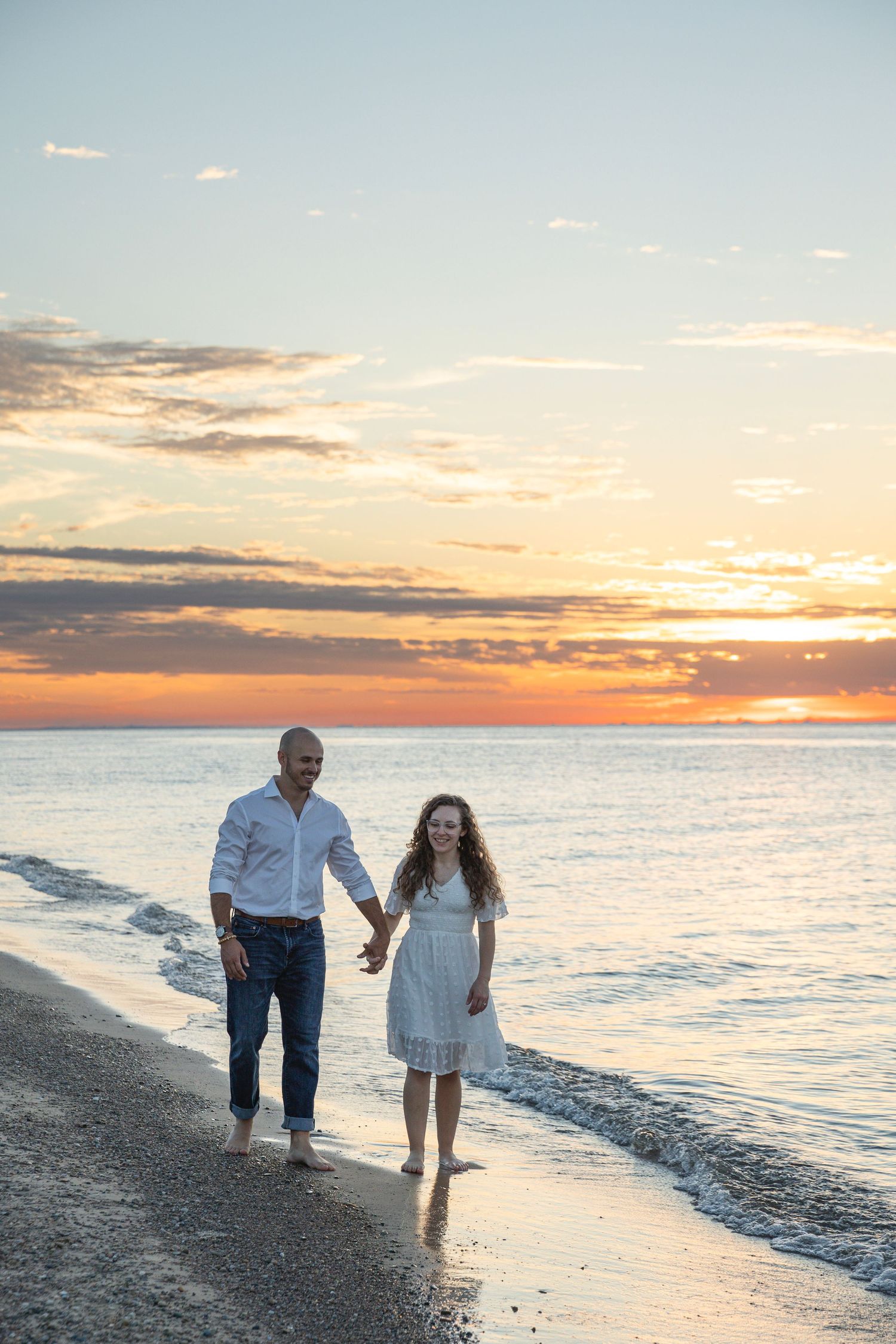 Engaged couple walking along a Lake Michigan beach in Indiana during a natural, candid engagement session.