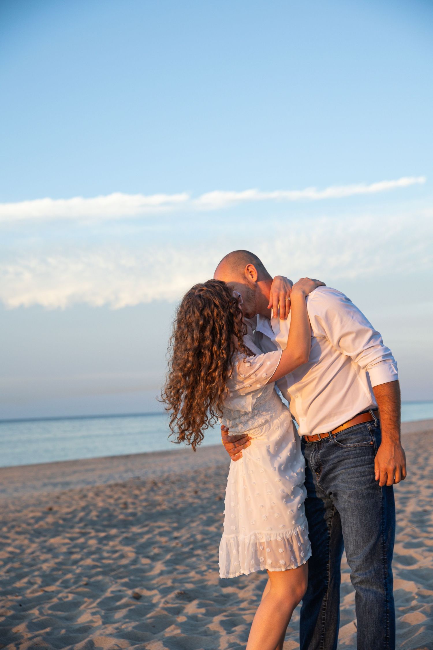 Engaged couple embracing along a Lake Michigan beach in Indiana during a natural, candid engagement session.