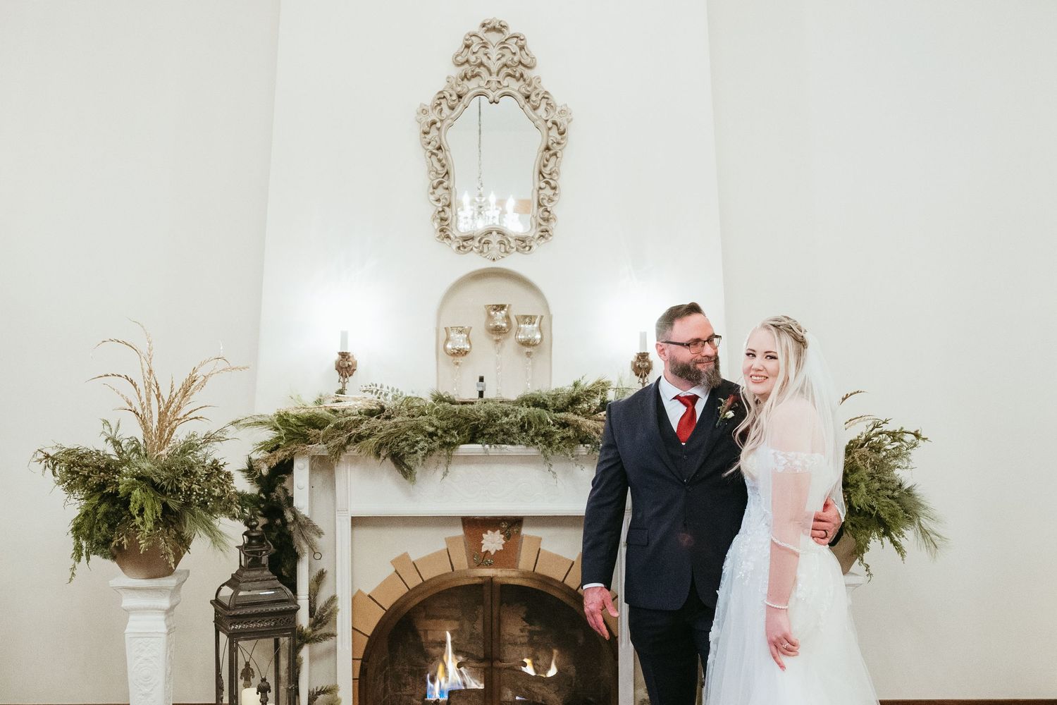 Bride and groom portrait at a winter wedding in Michigan standing together indoors beside a cozy fireplace