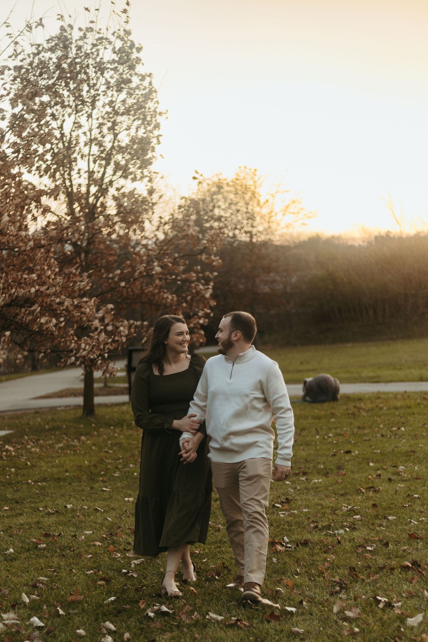 Golden hour couples photo session in Ann Arbor, Michigan featuring a couple walking together through a park in soft autumn light