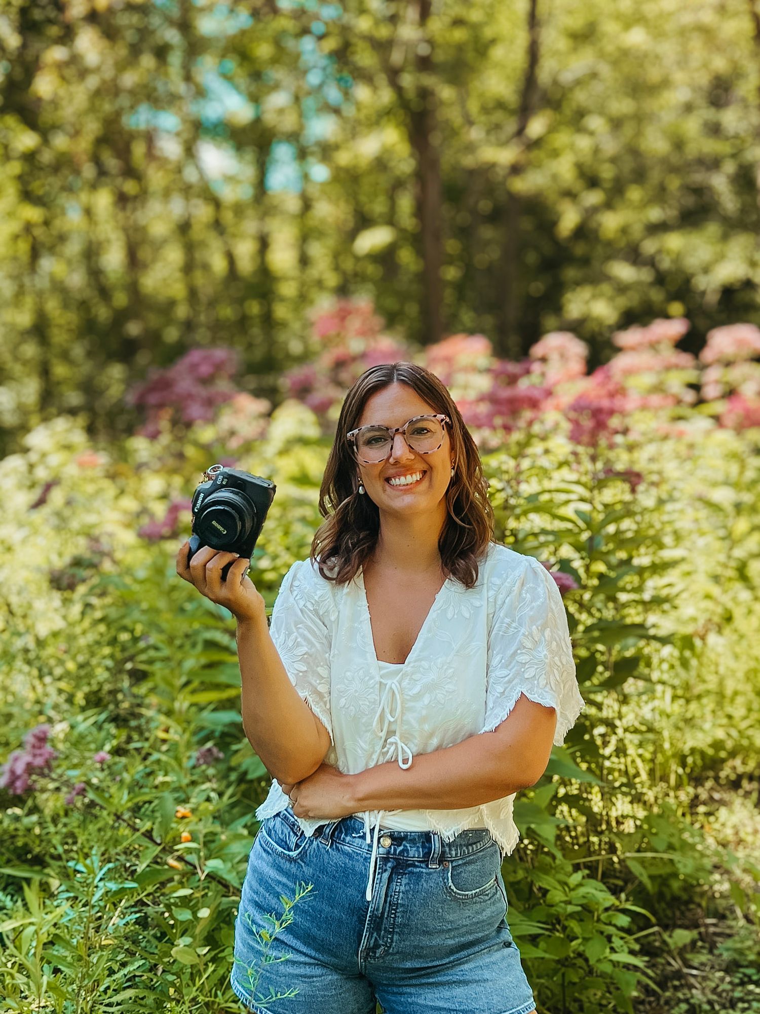 Southeast Michigan wedding and lifestyle photographer based in Lapeer smiling outdoors with camera in hand