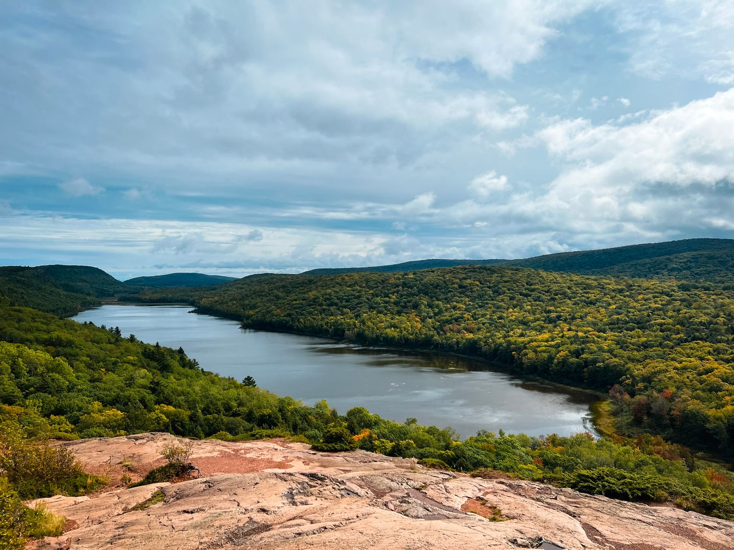 Summer view of Lake of the Clouds surrounded by lush green foliage and rolling hills