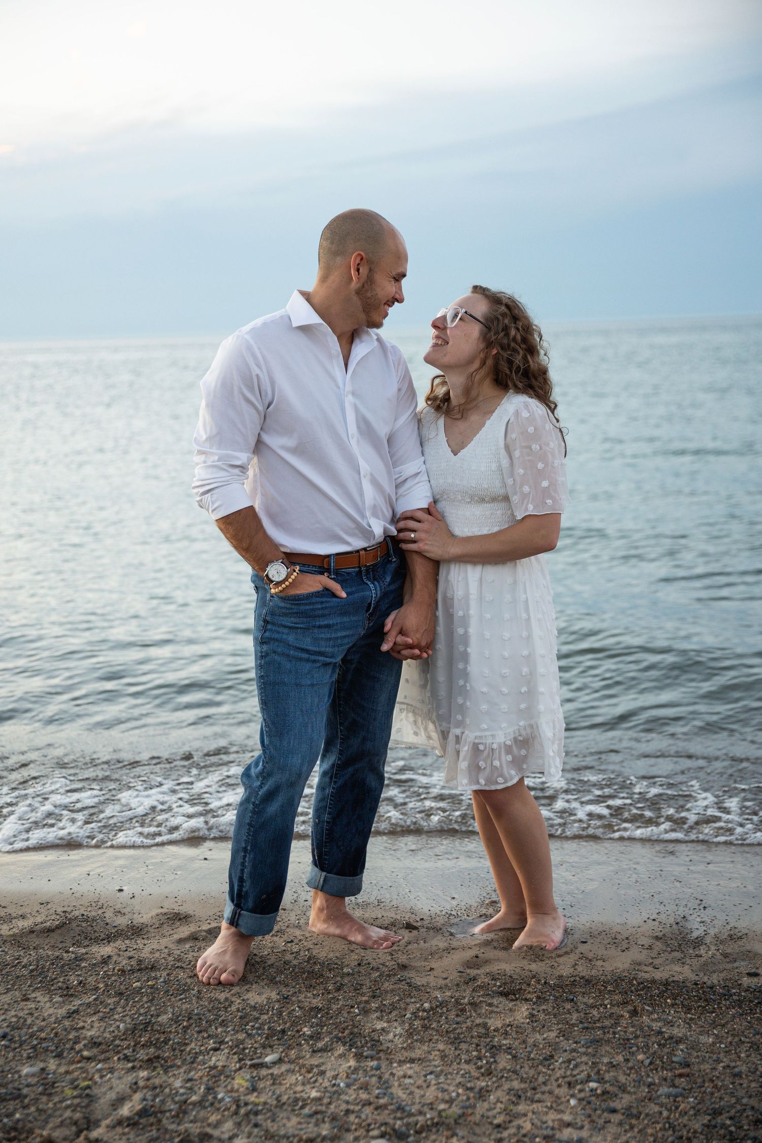 Engaged couple walking along a Lake Michigan beach in Indiana during a natural, candid engagement session.