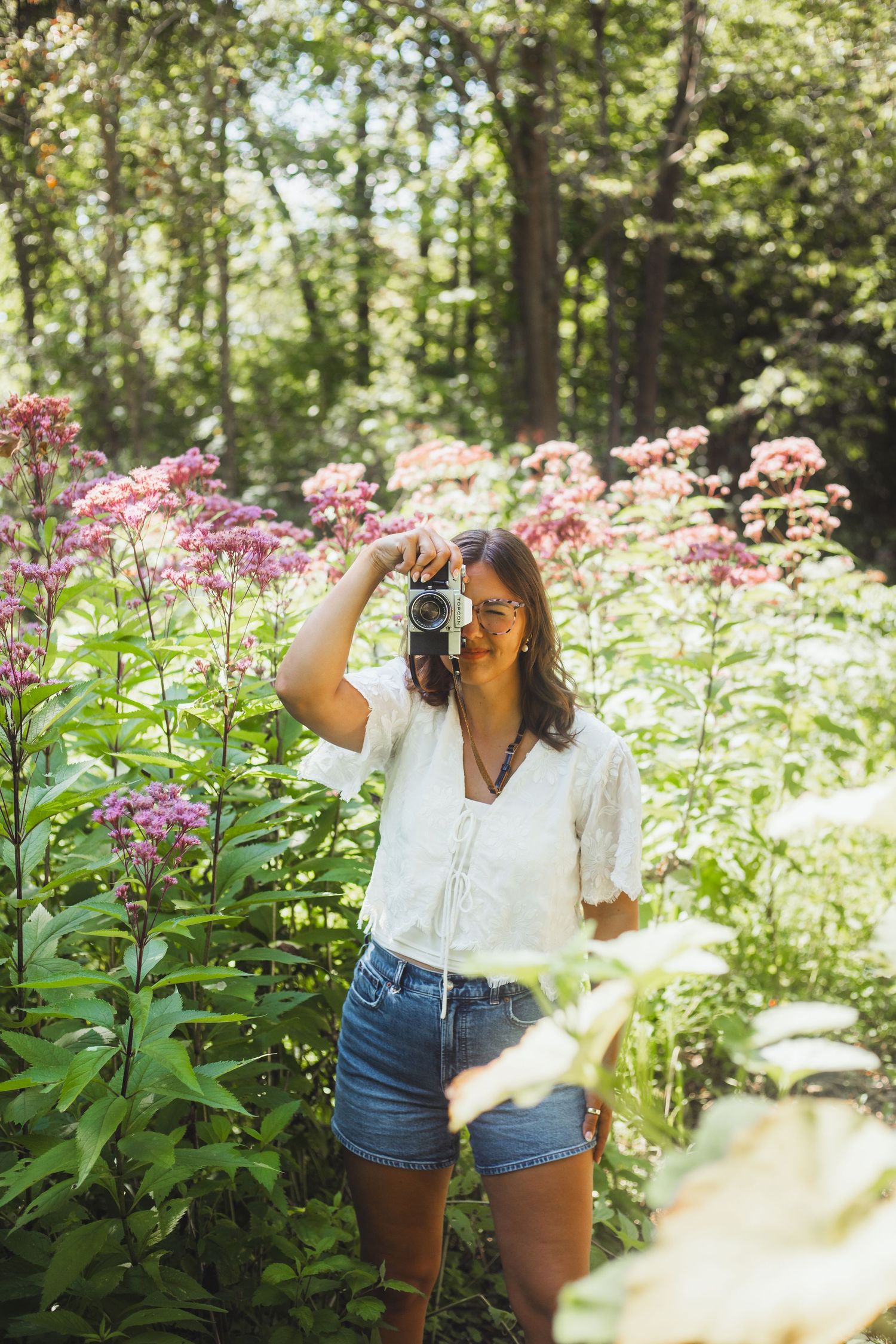 Lapeer Michigan photographer taking a photo on a film camera in the wild flowers
