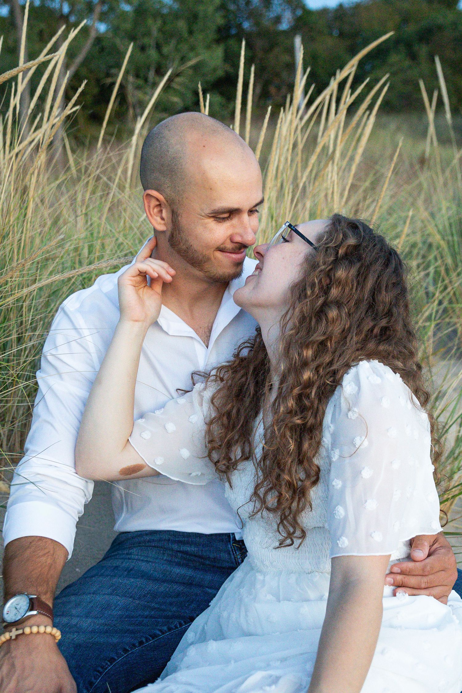 Engaged couple embracing along a Lake Michigan beach in Indiana during a natural, candid engagement session.