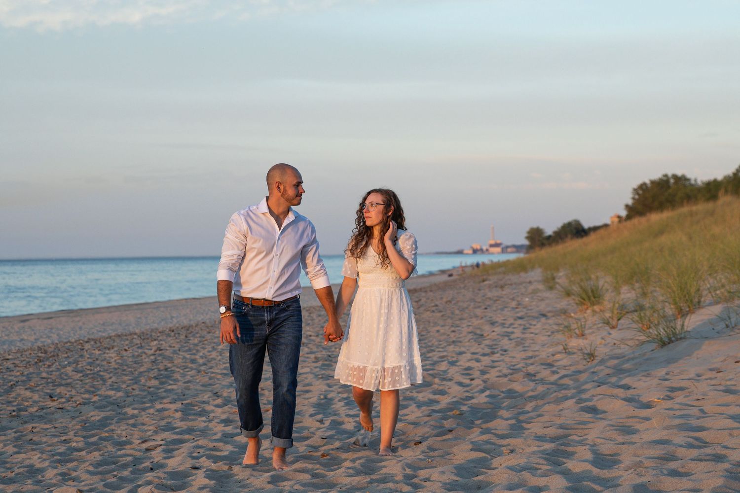Engaged couple walking along a Lake Michigan beach in Indiana during a natural, candid engagement session.