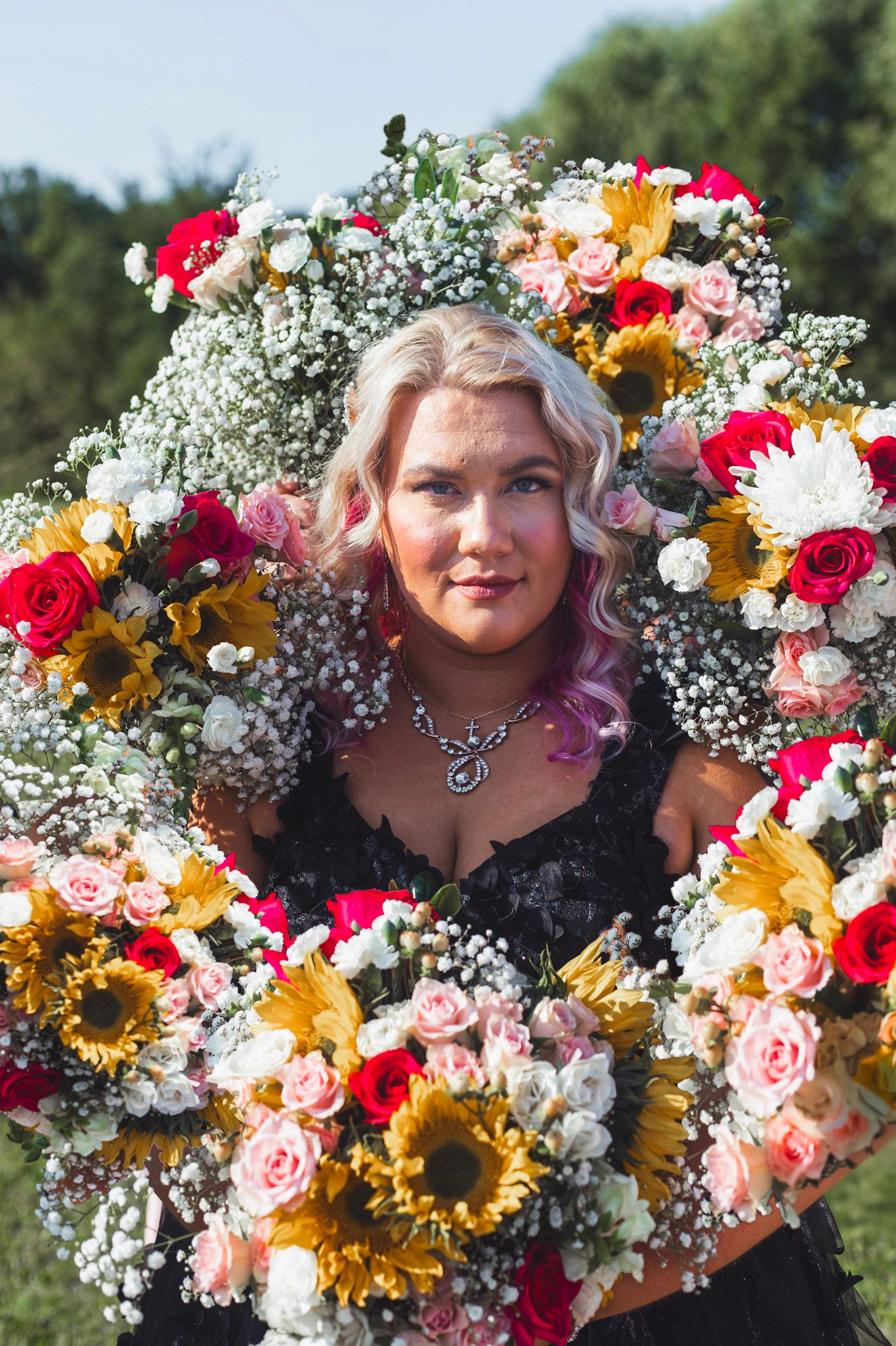 Bride surrounded by colorful flower bouquets during a Flint, Michigan wedding in a bright outdoor setting