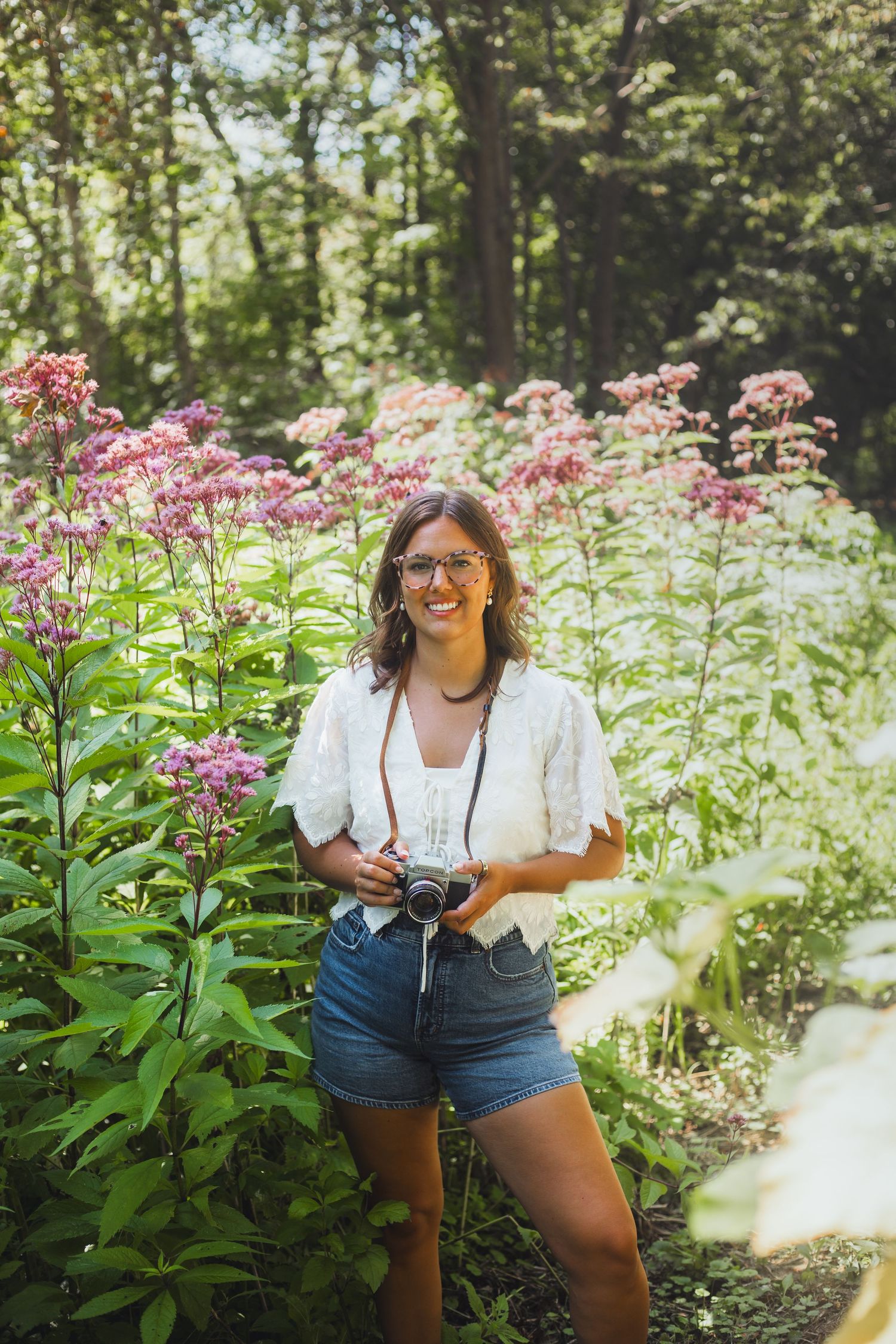 Lapeer Michigan photographer taking a photo on a film camera in the wild flowers