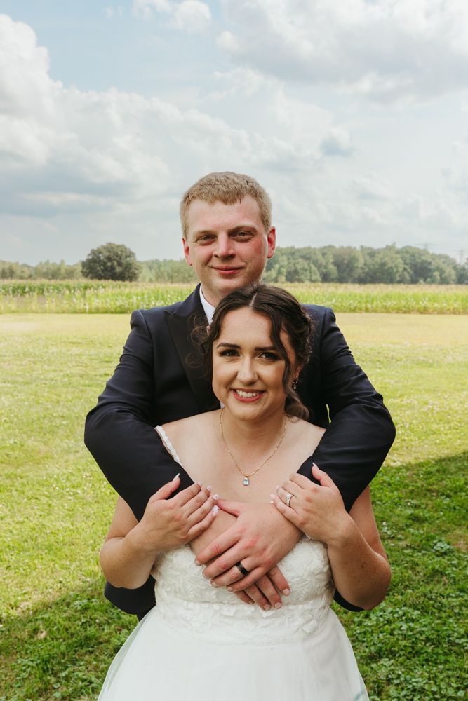 Romantic outdoor wedding portrait from an August wedding in New Boston, Michigan showing bride holding groom’s face