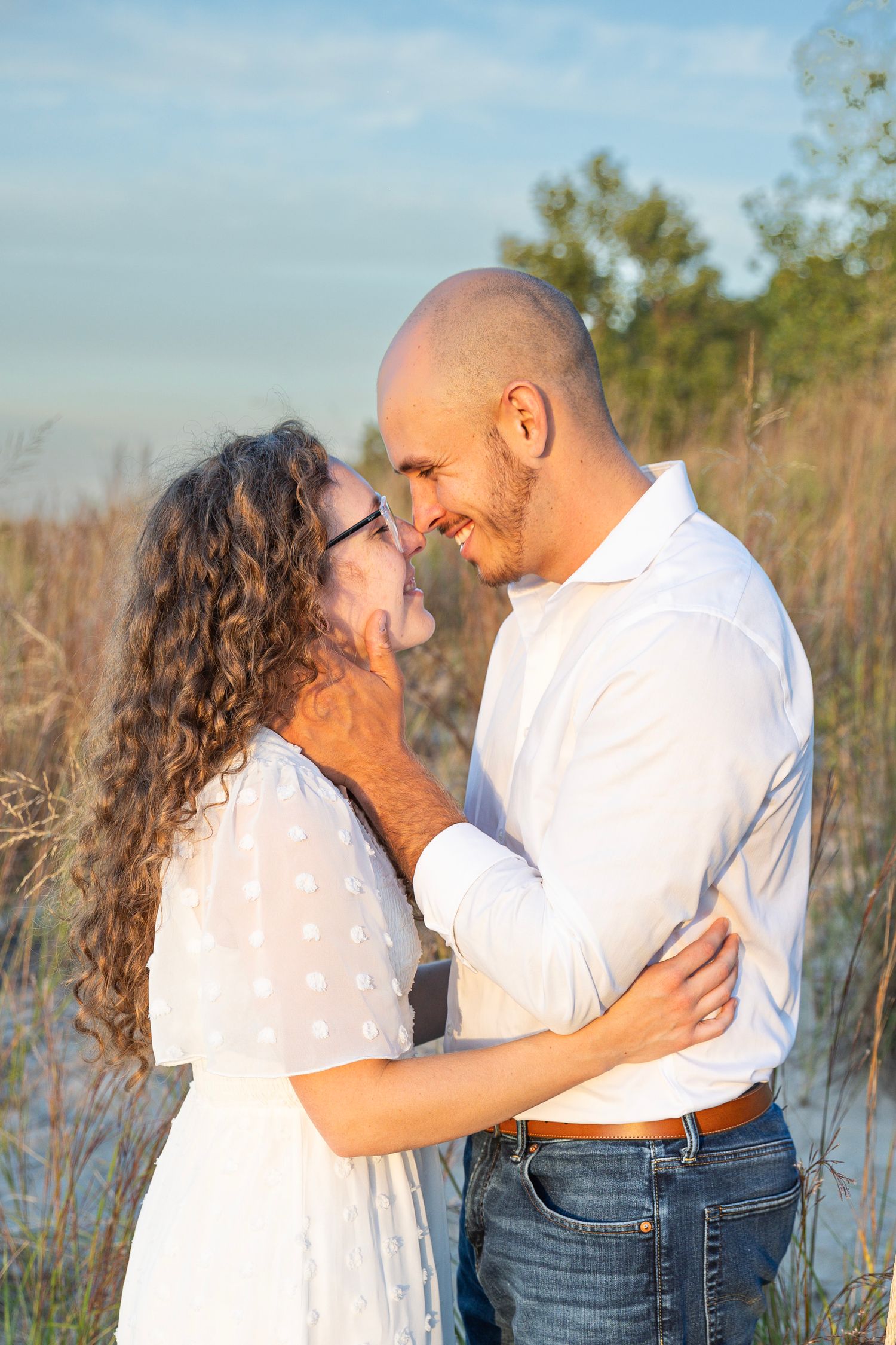 Engaged couple embracing along a Lake Michigan beach in Indiana during a natural, candid engagement session.