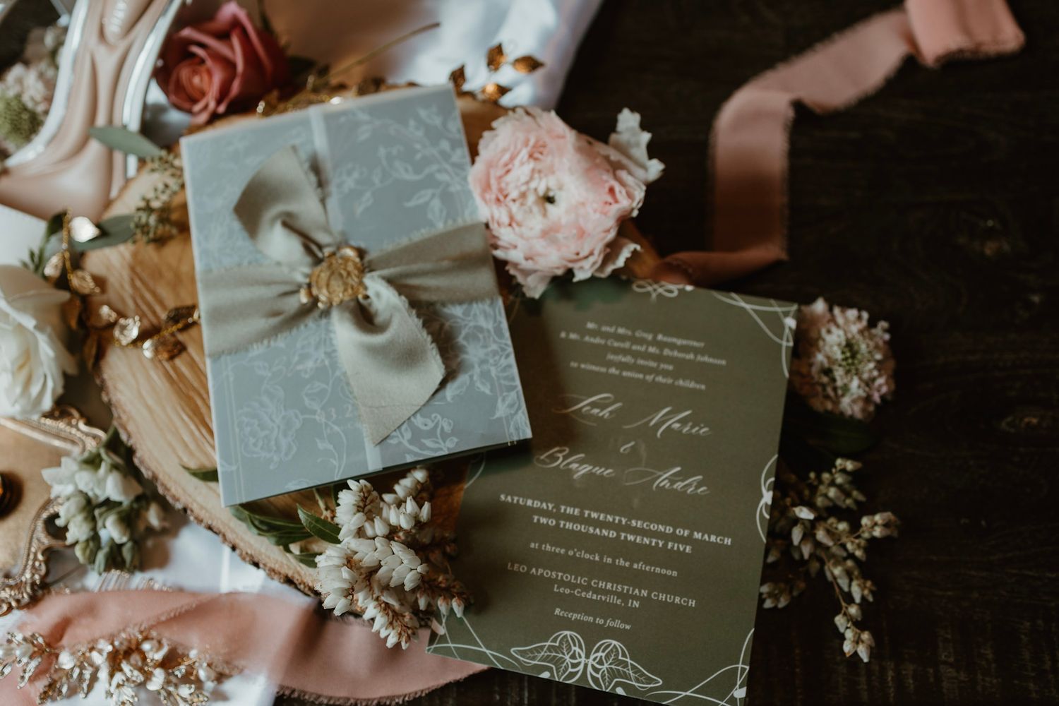Elegant sage green wedding invitation suite with wax seal ribbon bow surrounded by blush flowers.