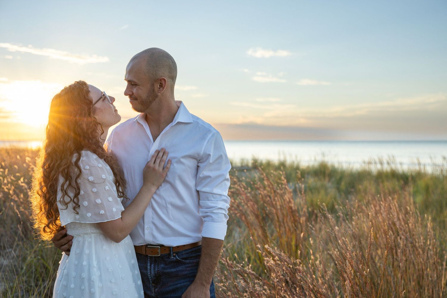 Engaged couple embracing along a Lake Michigan beach in Indiana during a natural, candid engagement session.