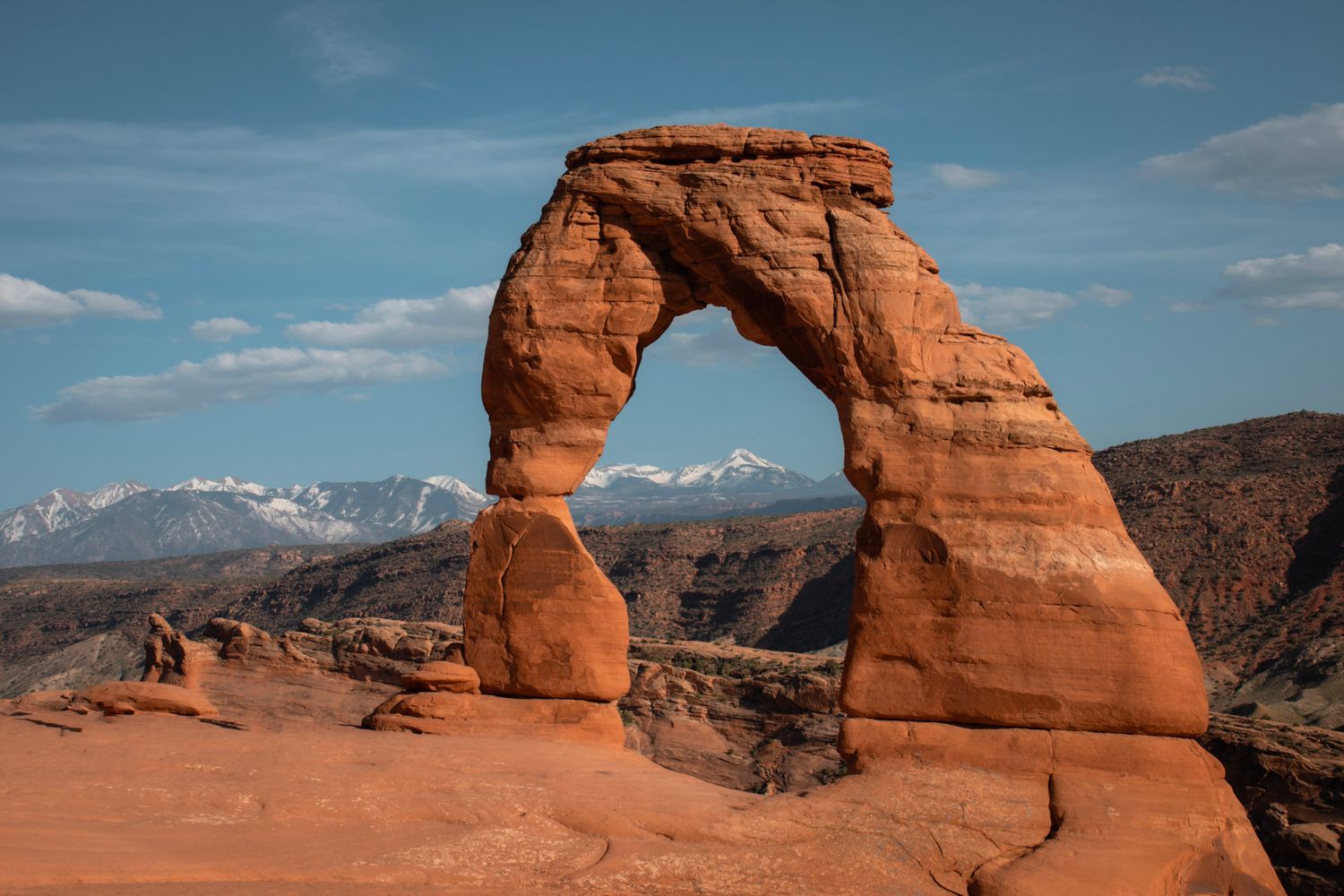 Delicate Arch in Arches National Park framed by red rock desert landscape under a soft blue sky