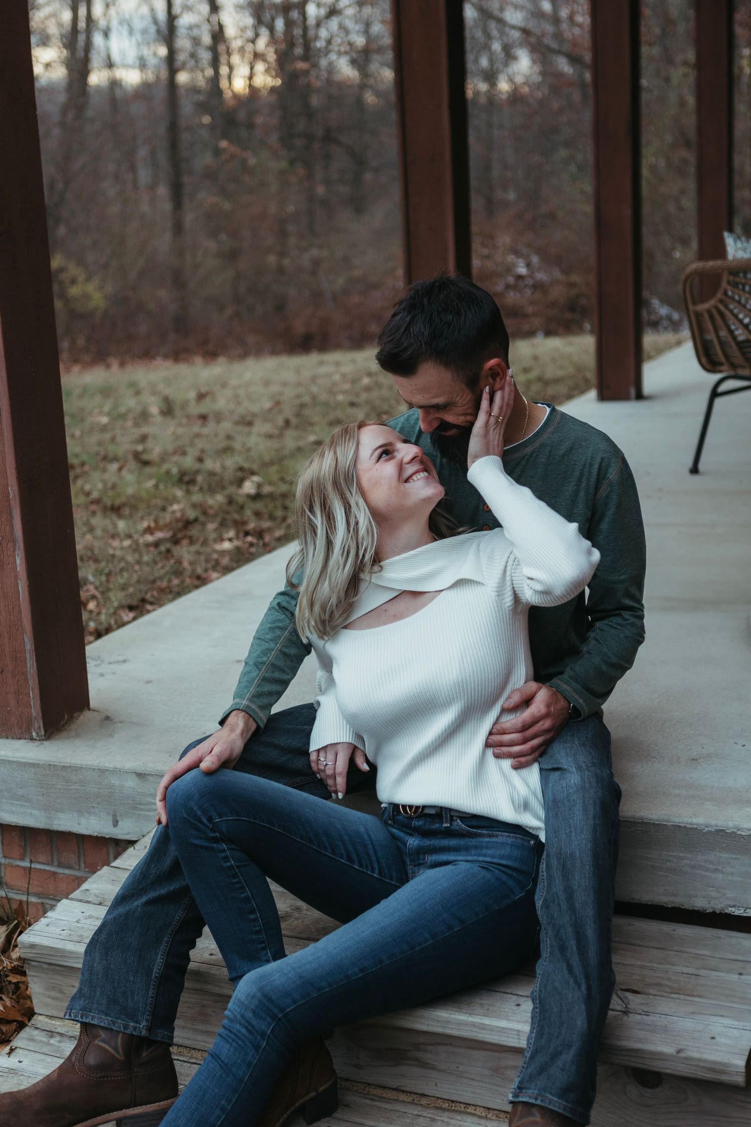 Cozy winter engagement session in Lapeer, Michigan with a couple standing together on a porch in soft natural light