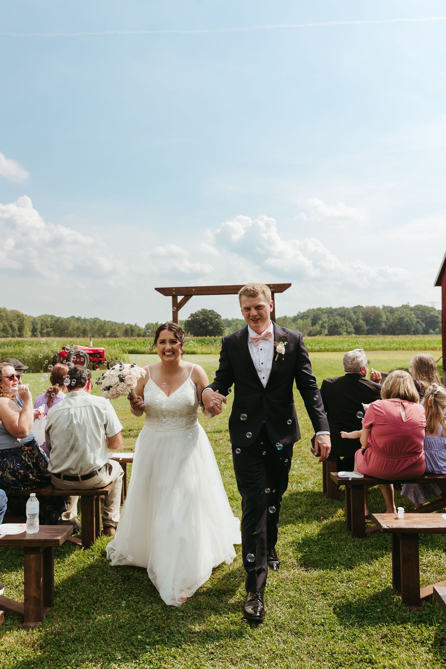 Just married couple exiting an outdoor wedding ceremony in New Boston, Michigan during an August wedding