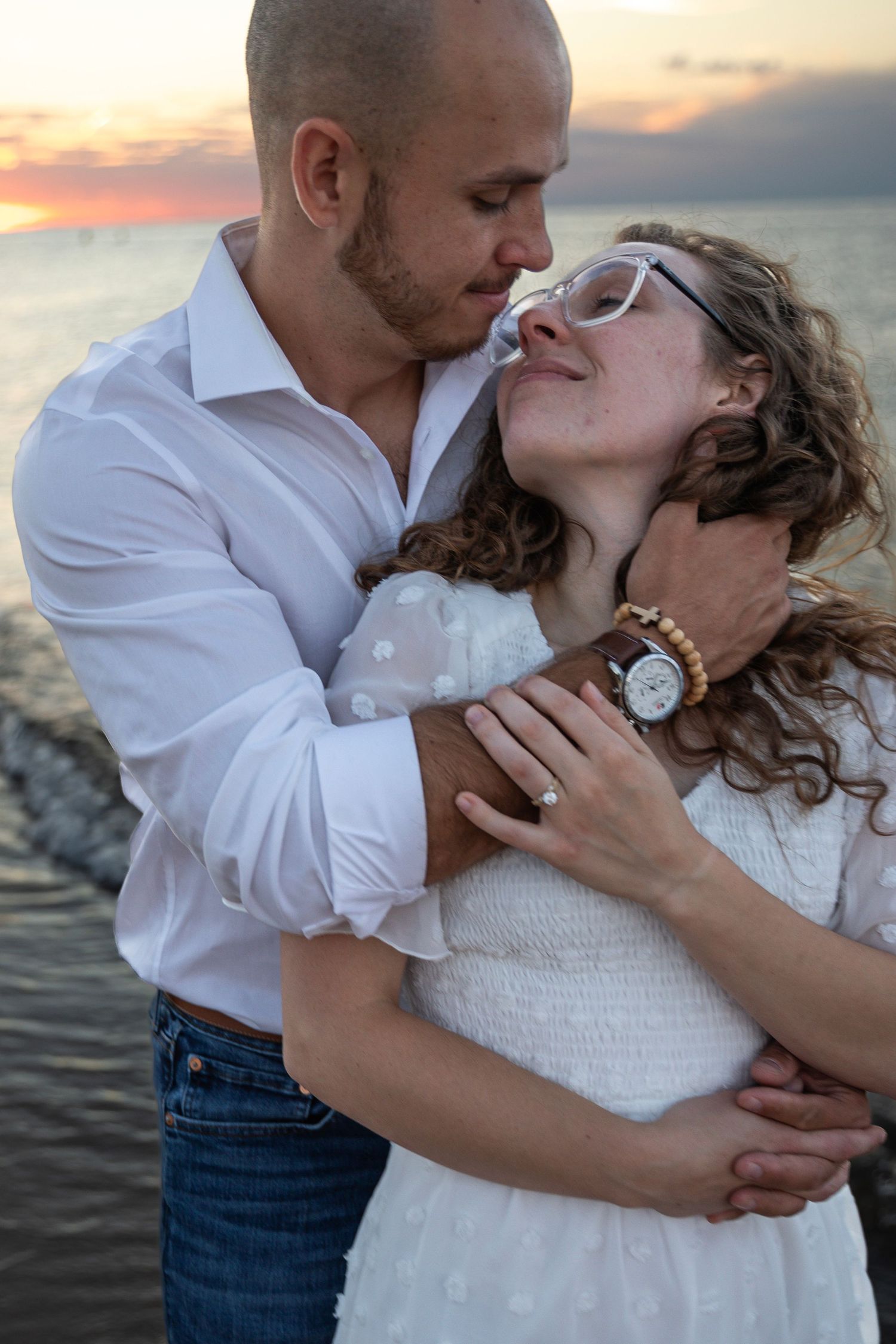 Engaged couple embracing along a Lake Michigan beach in Indiana during a natural, candid engagement session.