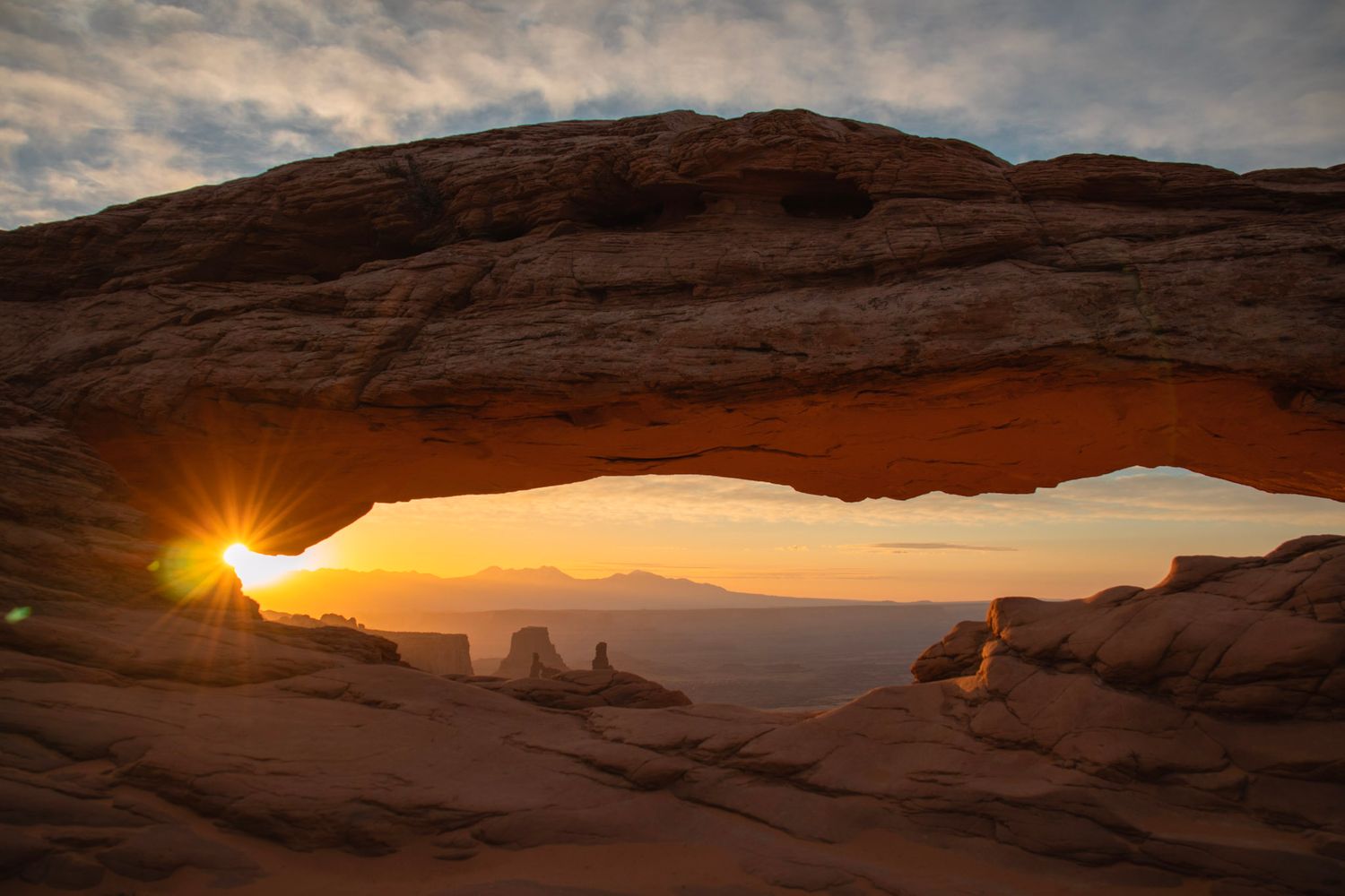 Sunrise at Mesa Arch with the sun illuminating the arch and canyon below in Canyonlands National Park