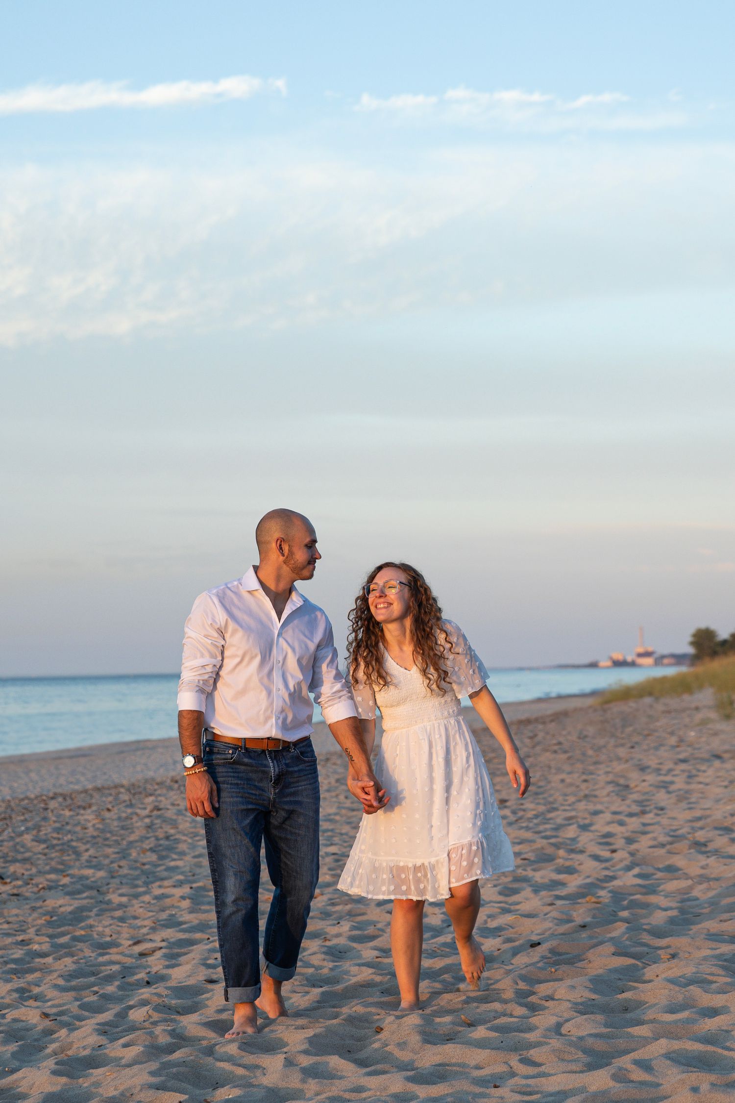 Engaged couple walking along a Lake Michigan beach in Indiana during a natural, candid engagement session.