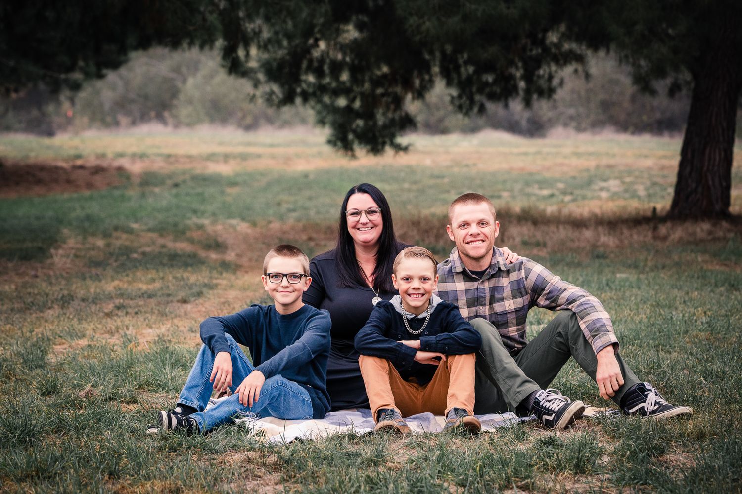 Family of four sitting casually on grass at the Bonsall Preserve for a relaxed outdoor portrait session