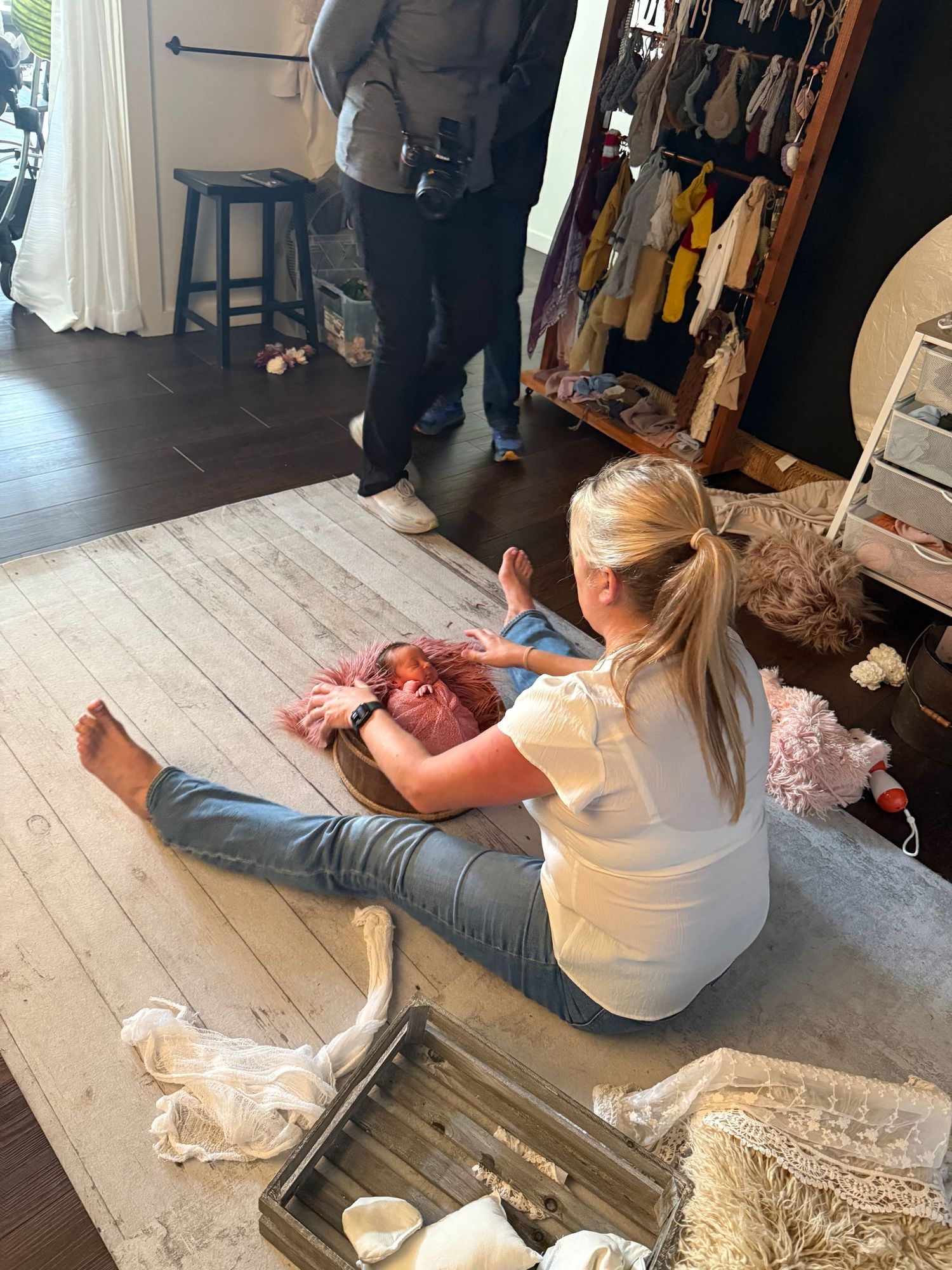 Photographer capturing a newborn baby during a professional photo shoot session in a boutique studio setting.