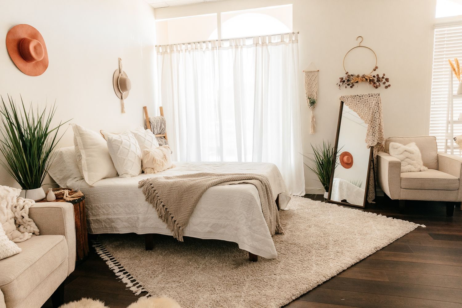 Boho chic bedroom with white bedding, shag rug, macrame wall art, sheer curtains, and neutral tones. in the Bonsall Studio near Fallbrook, V