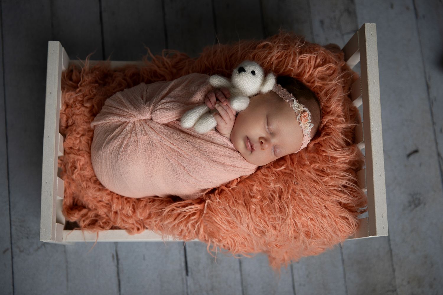 Swaddled newborn baby sleeping in wooden crate with orange fur and stuffed bunny toy. in Bonsall, near Fallbrook and Vista